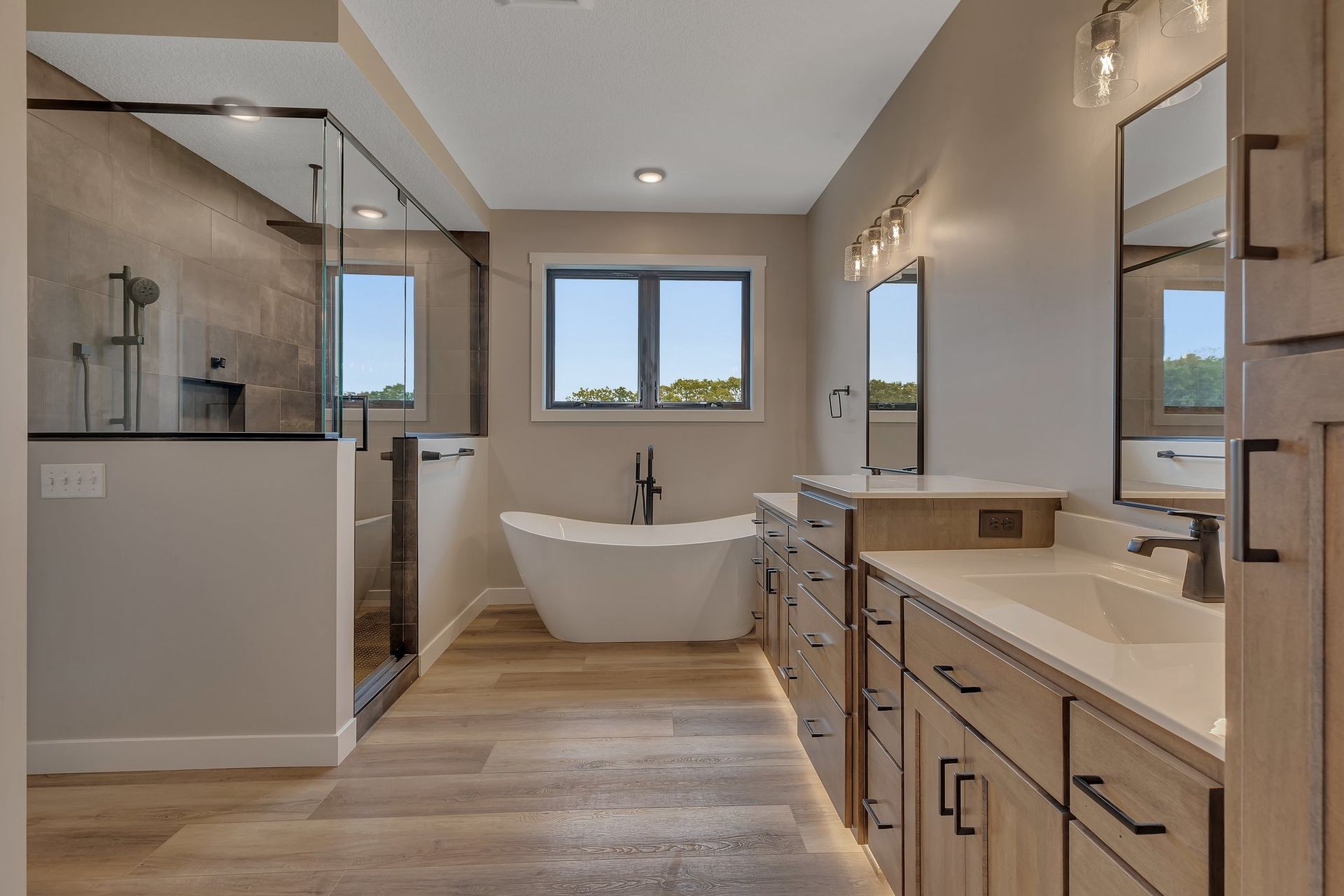 A bathroom with a tub , sinks , mirrors and a walk in shower.