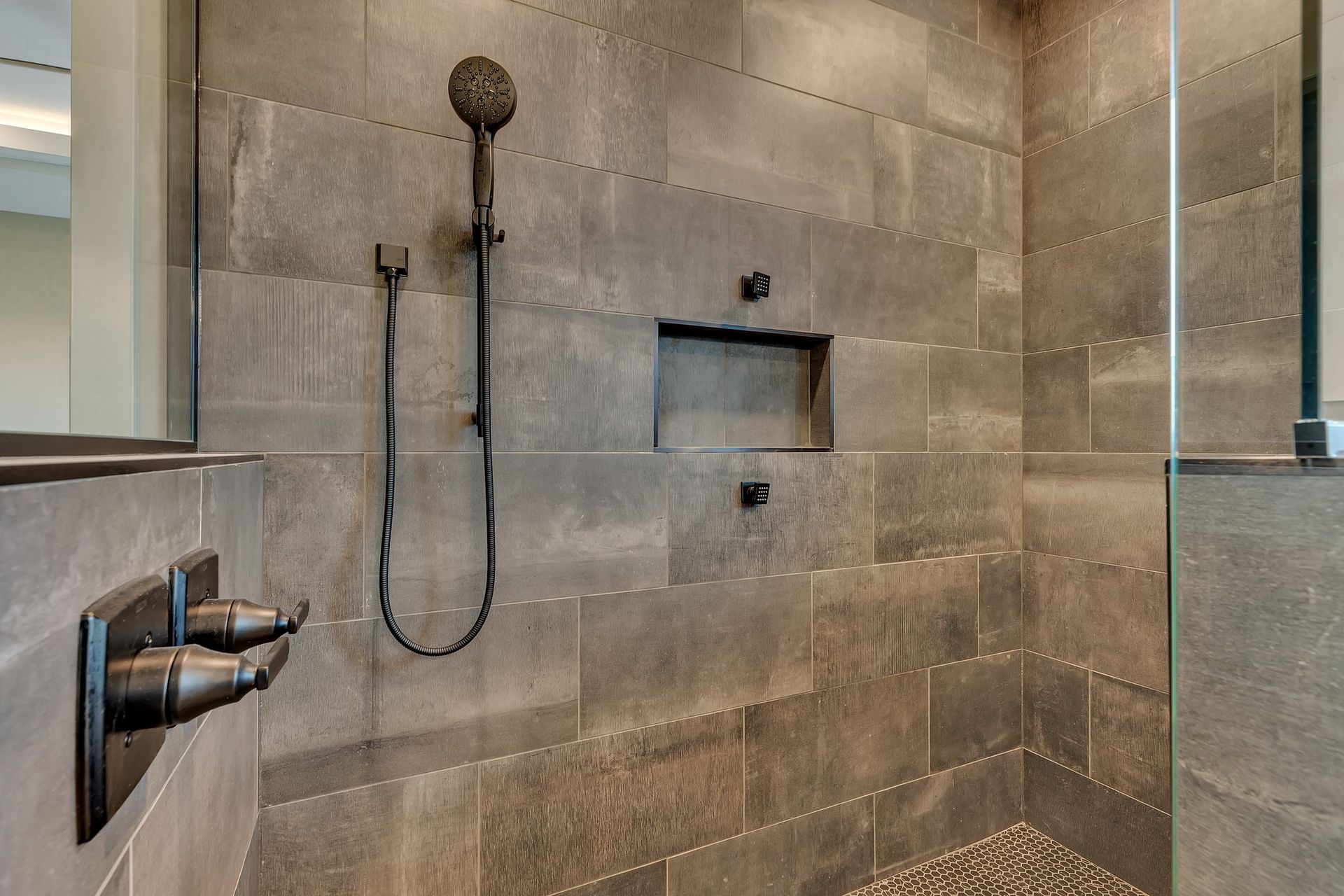 A bathroom with a walk in shower and a shower head.