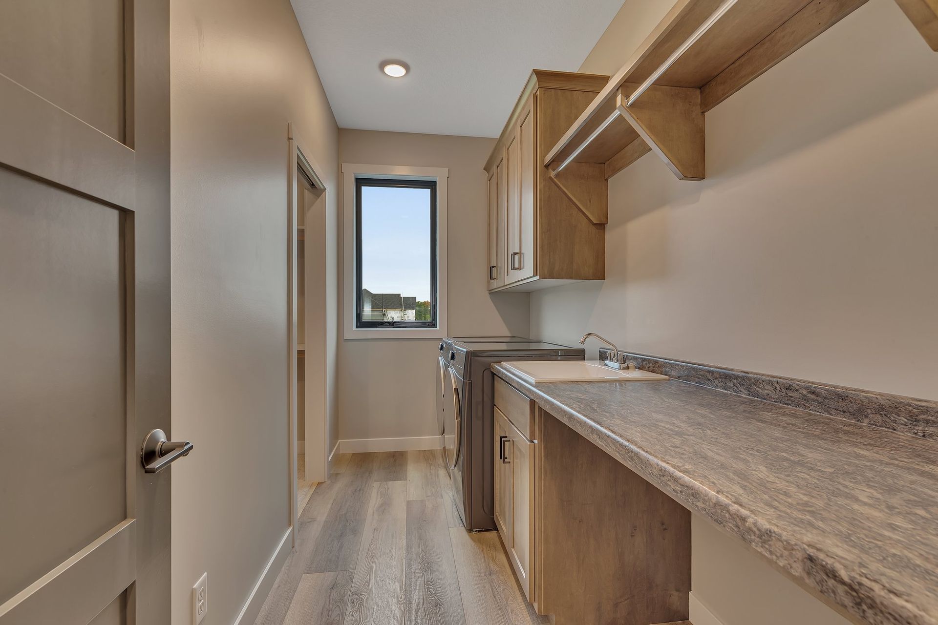 A laundry room with a sink , washer and dryer , and a window.