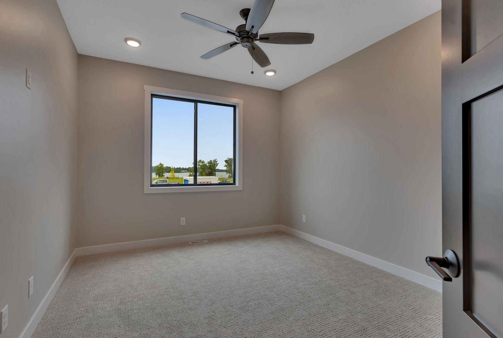 An empty bedroom with a ceiling fan and a window