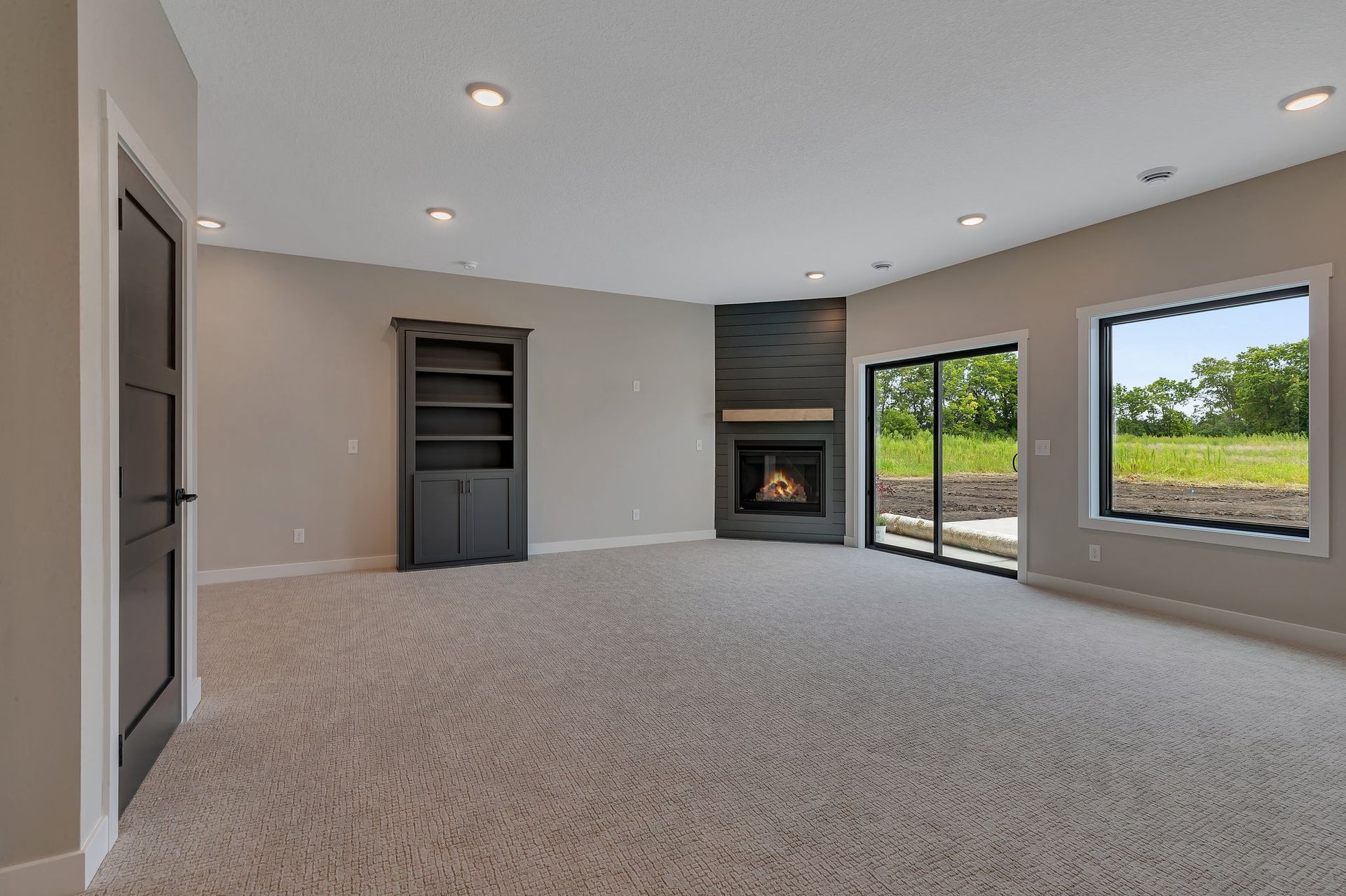 An empty living room with a fireplace and sliding glass doors.