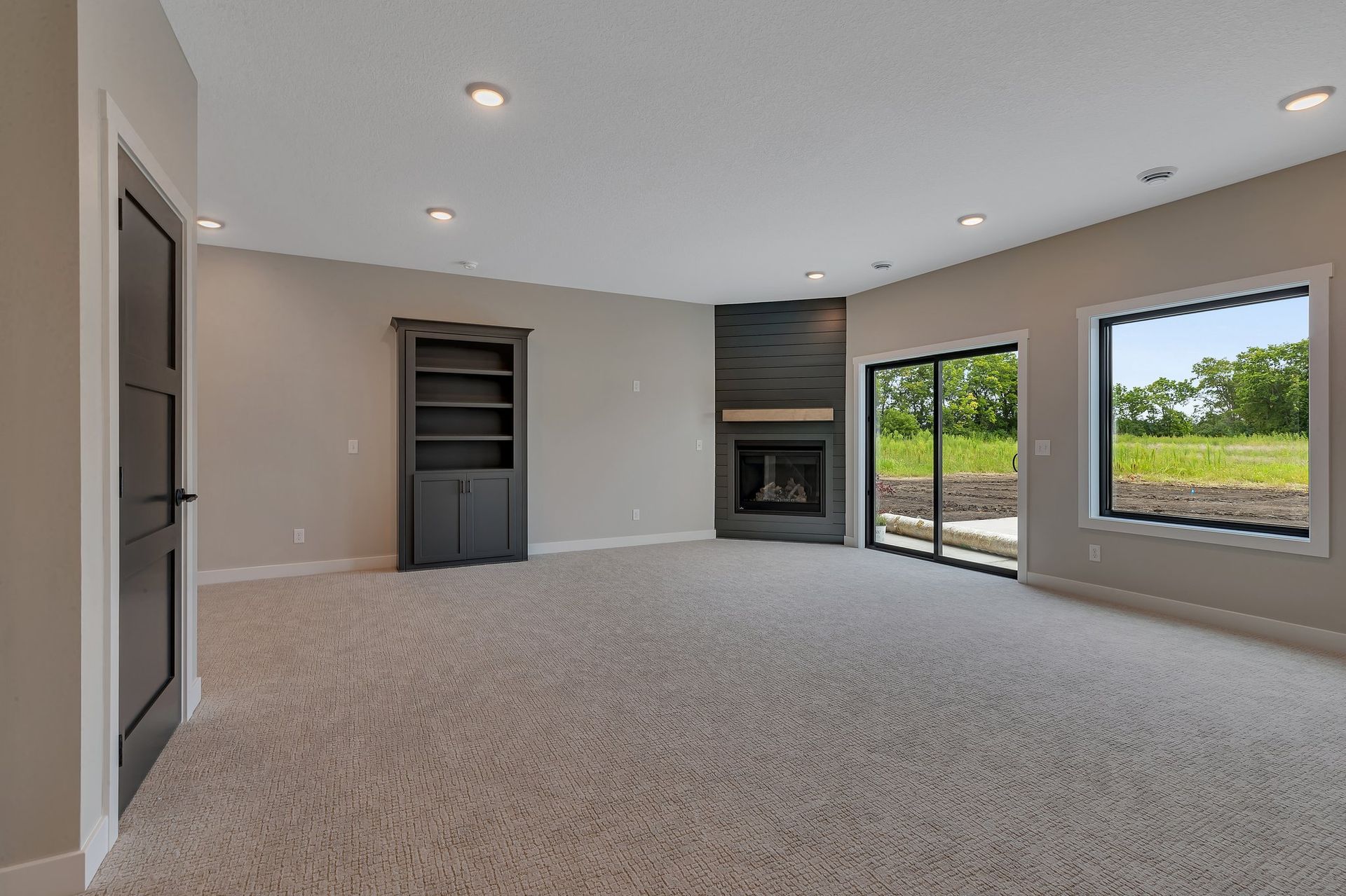 An empty living room with a fireplace and sliding glass doors.
