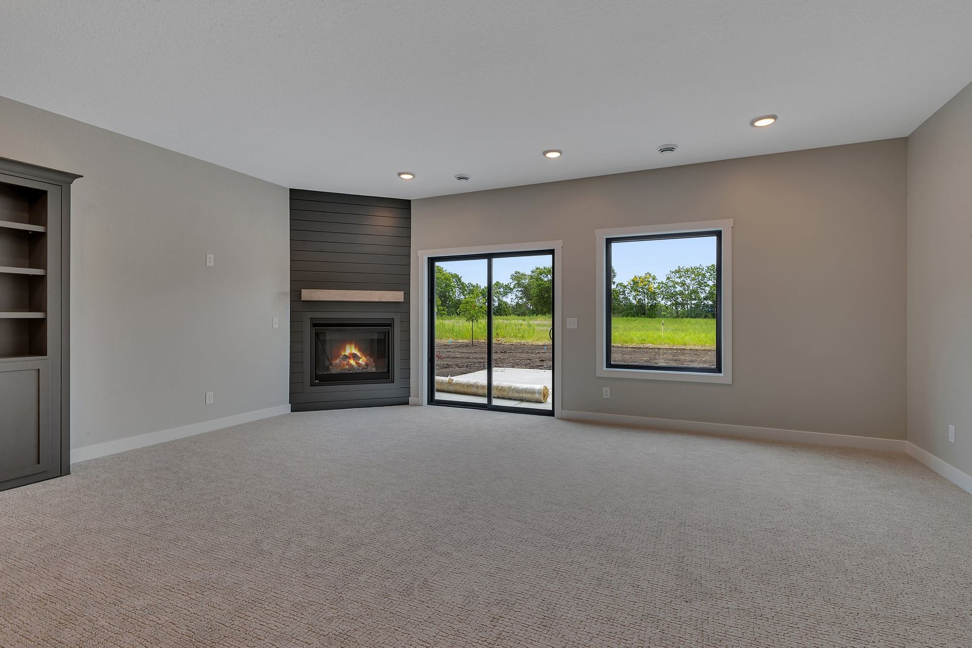 An empty living room with a fireplace and sliding glass doors.