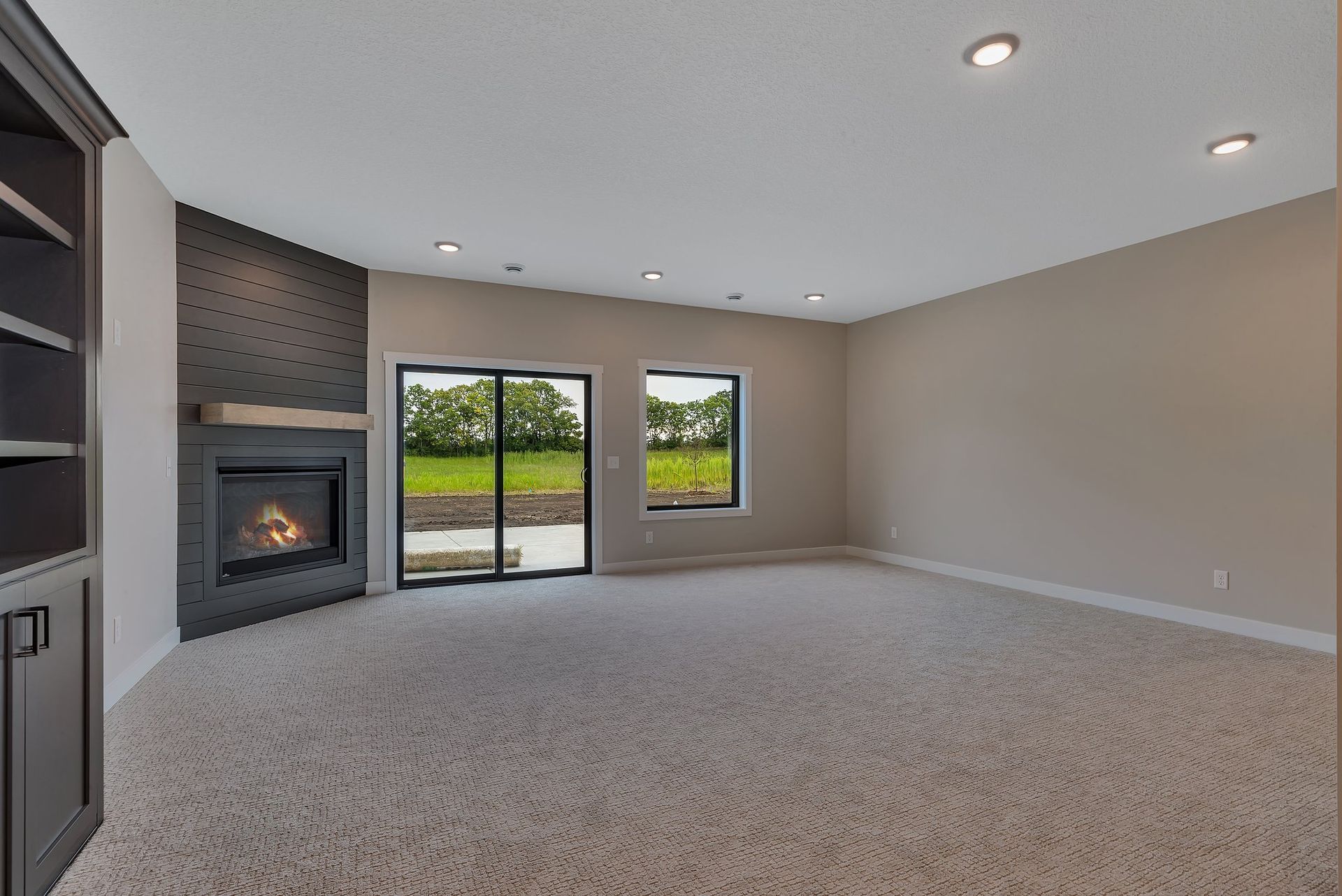 An empty living room with a fireplace and sliding glass doors.