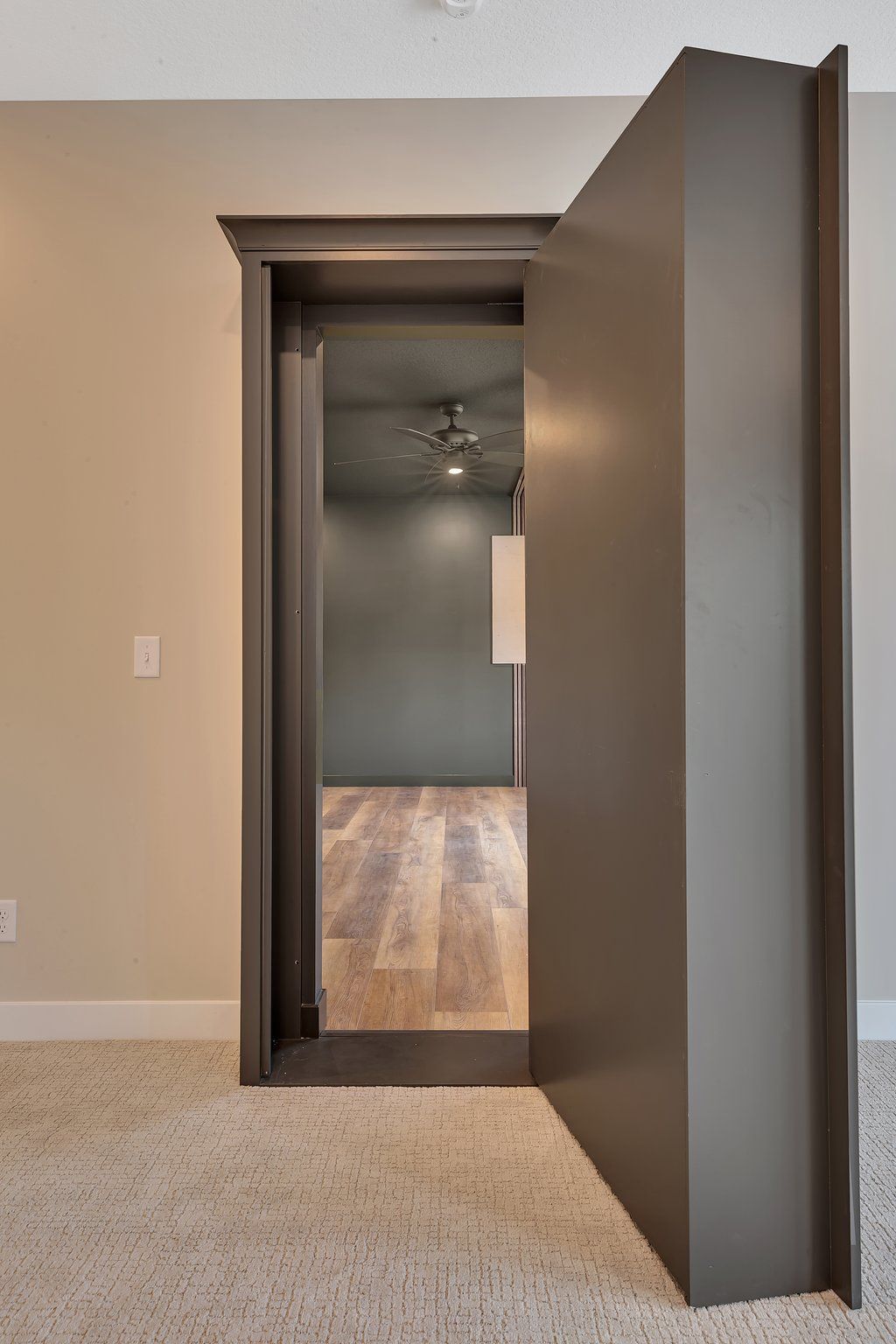 A doorway leading to a room with hardwood floors and a ceiling fan.