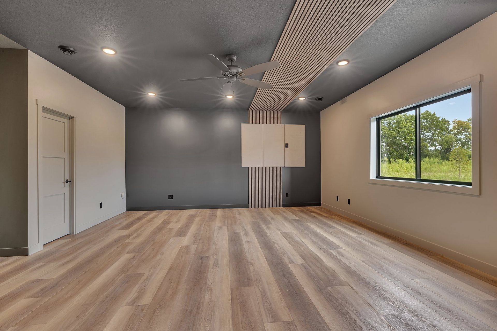 An empty room with hardwood floors and a ceiling fan.