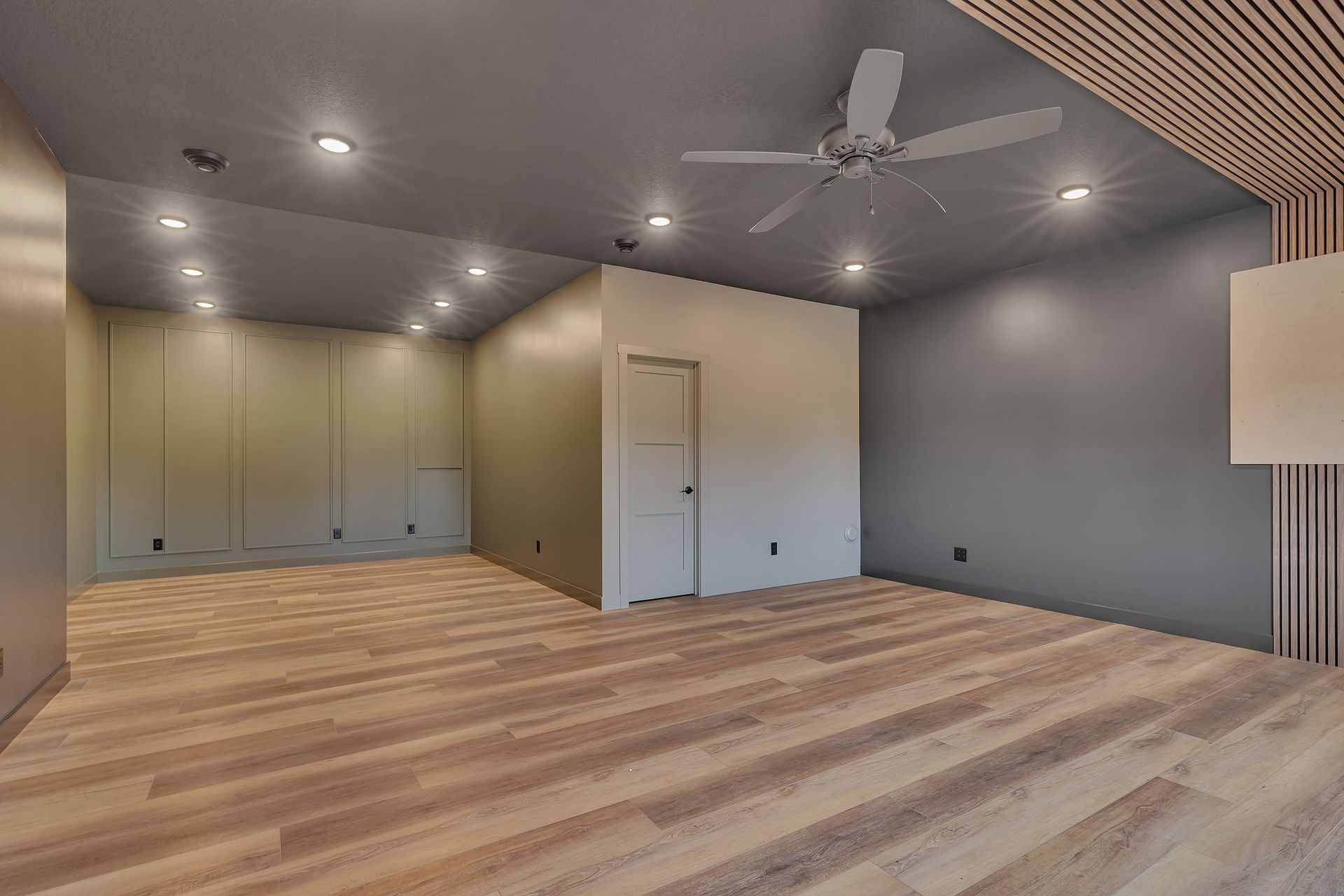 An empty room with hardwood floors and a ceiling fan.
