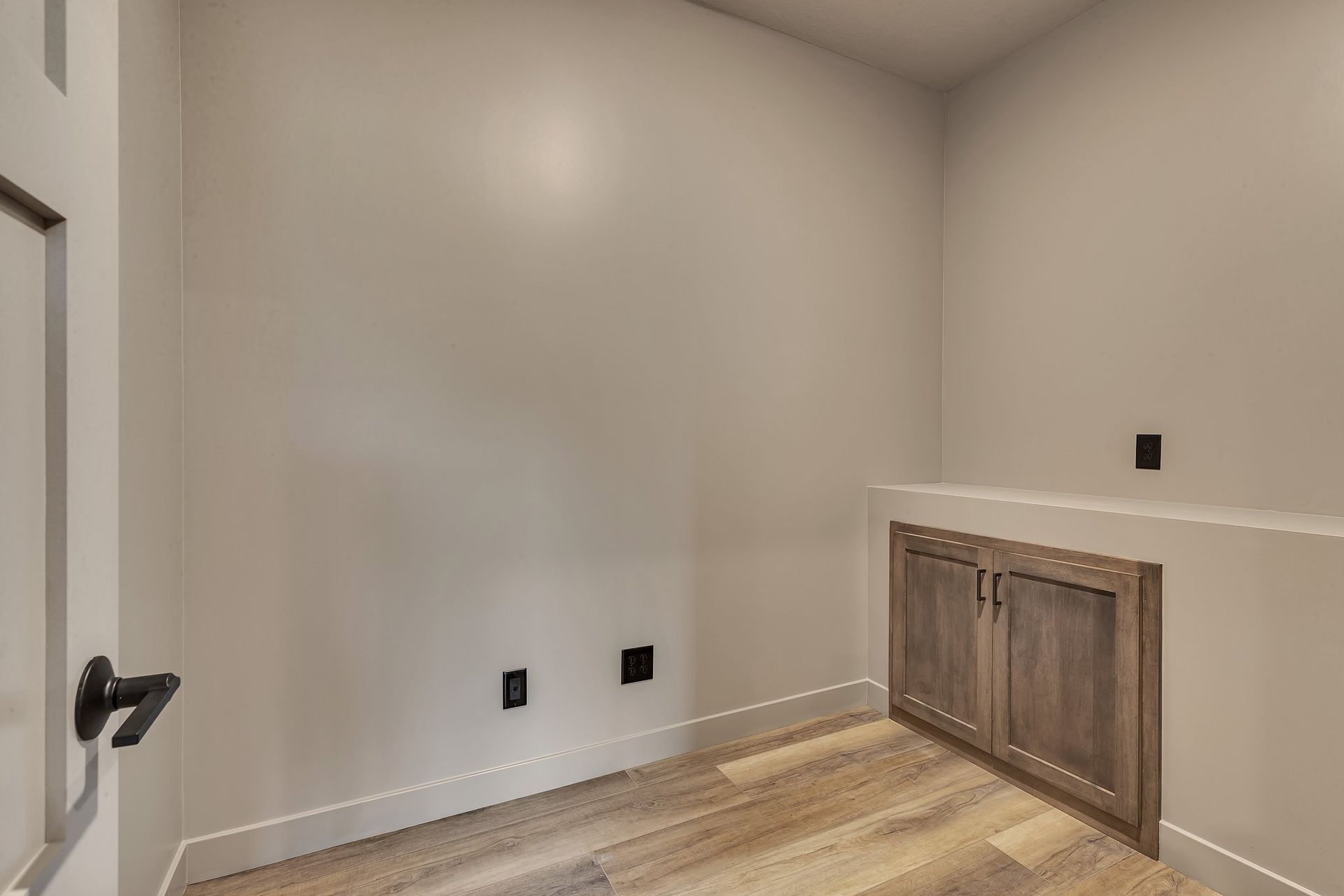 An empty room with a wooden floor and cabinets.