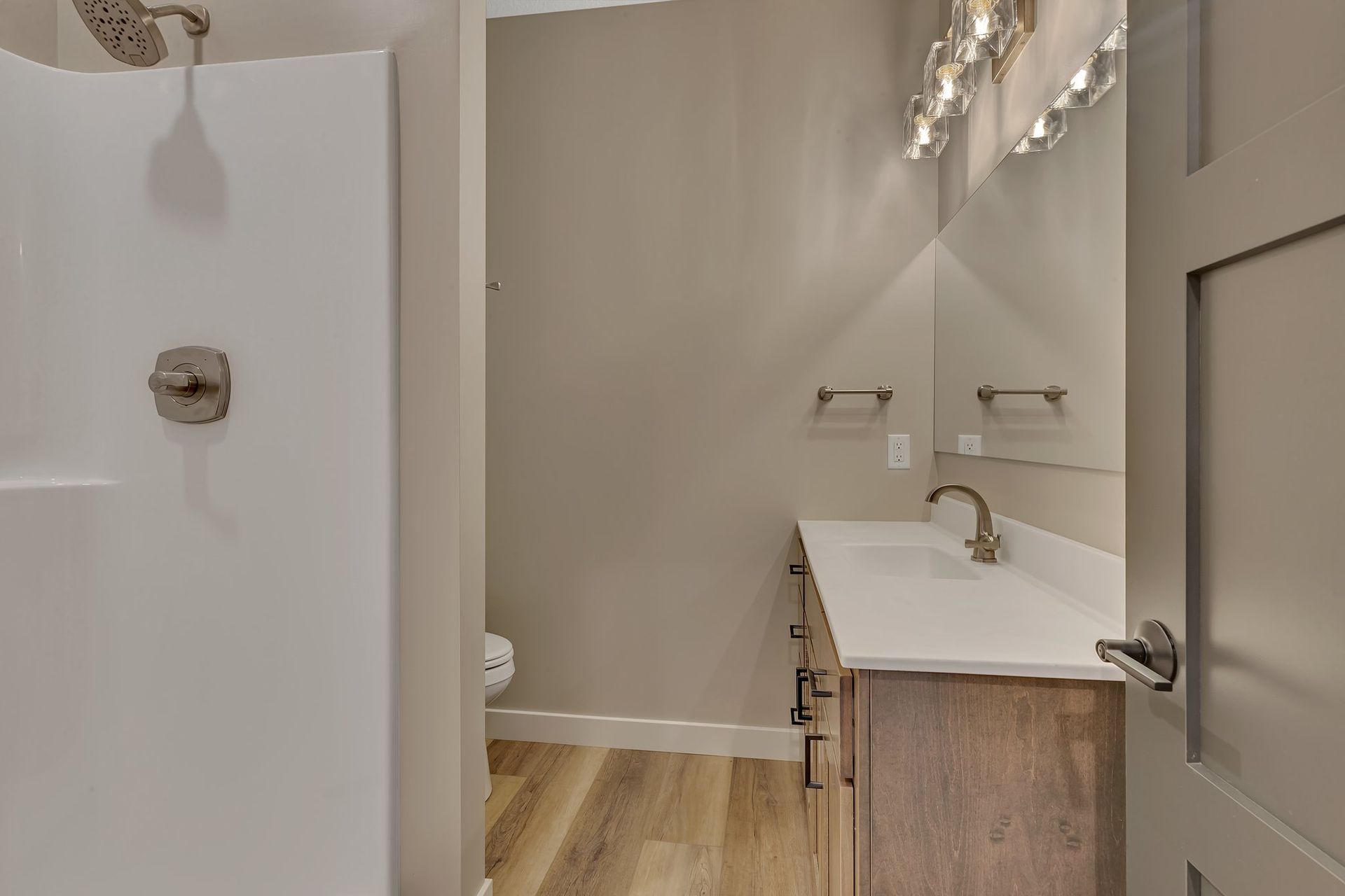 A bathroom with a sink , toilet , shower and mirror.