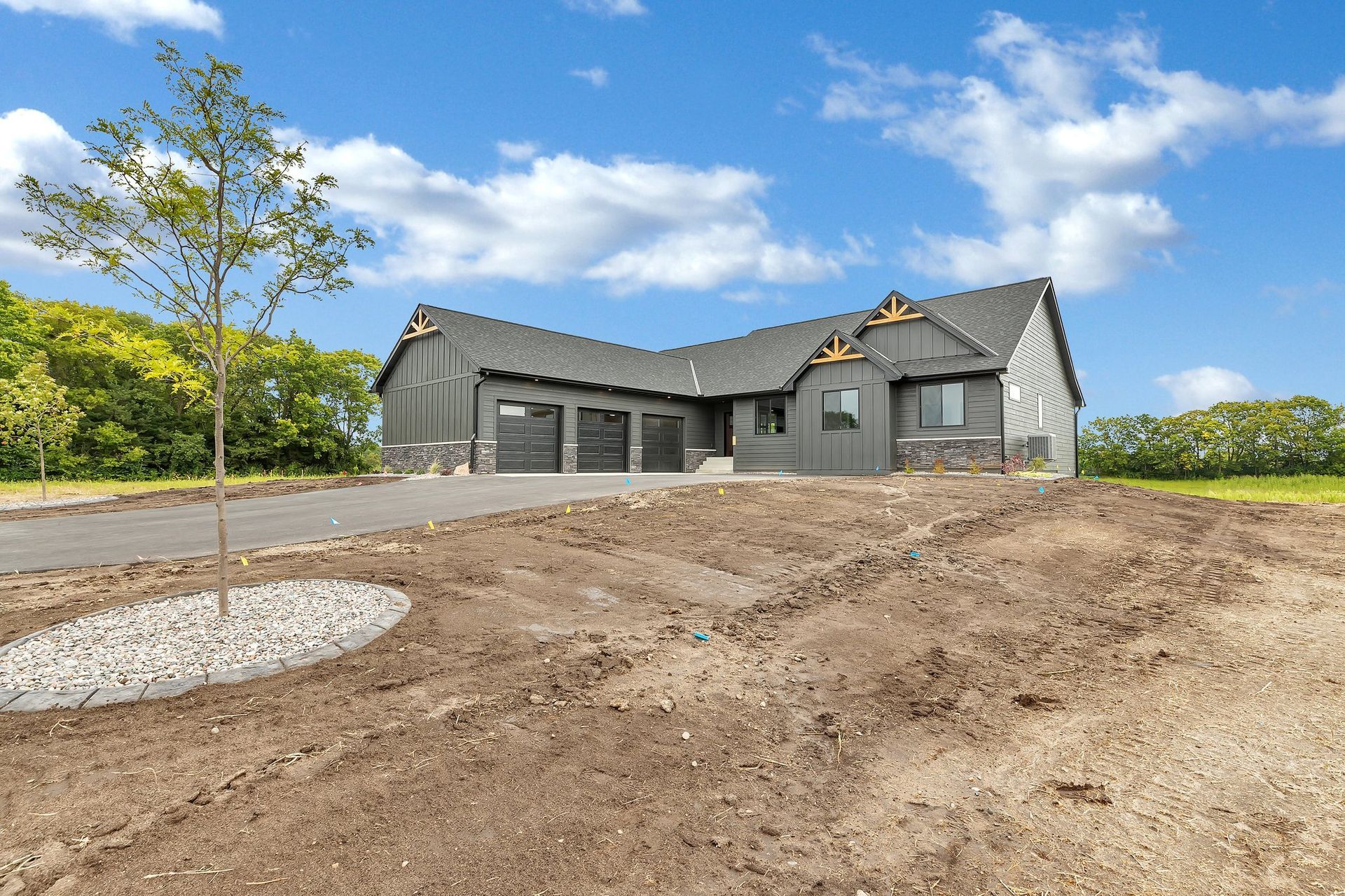 A house is sitting on top of a dirt hill next to a tree.