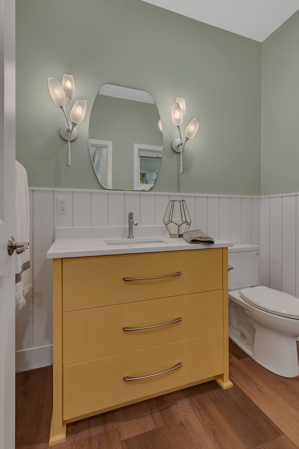 A bathroom with a yellow vanity , toilet and mirror.