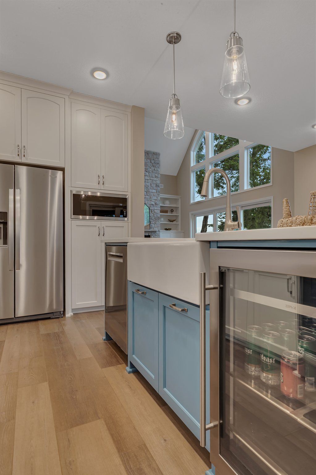 A kitchen with blue cabinets , stainless steel appliances , a refrigerator and a wine cooler.