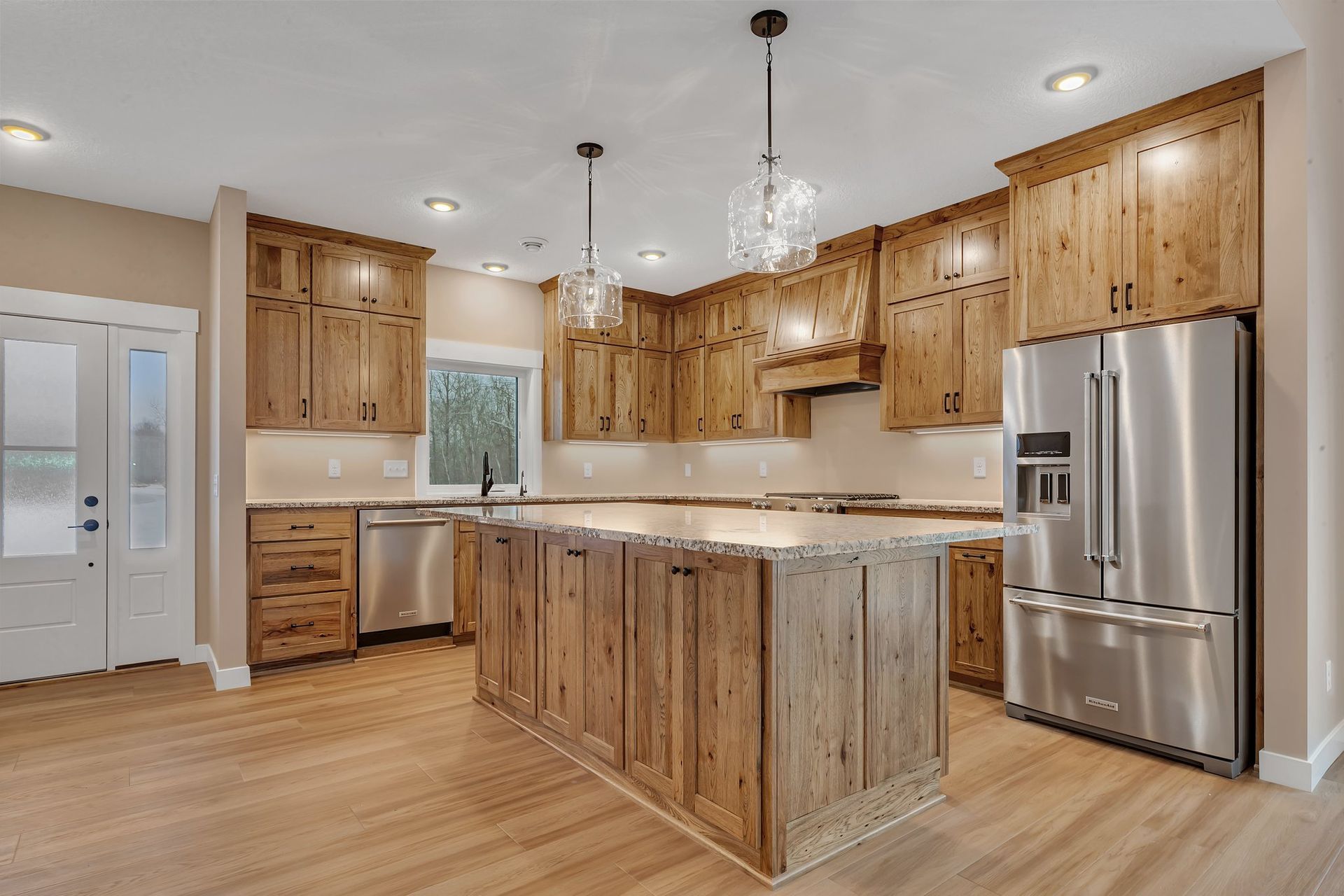 A kitchen with wooden cabinets , stainless steel appliances , and a large island.