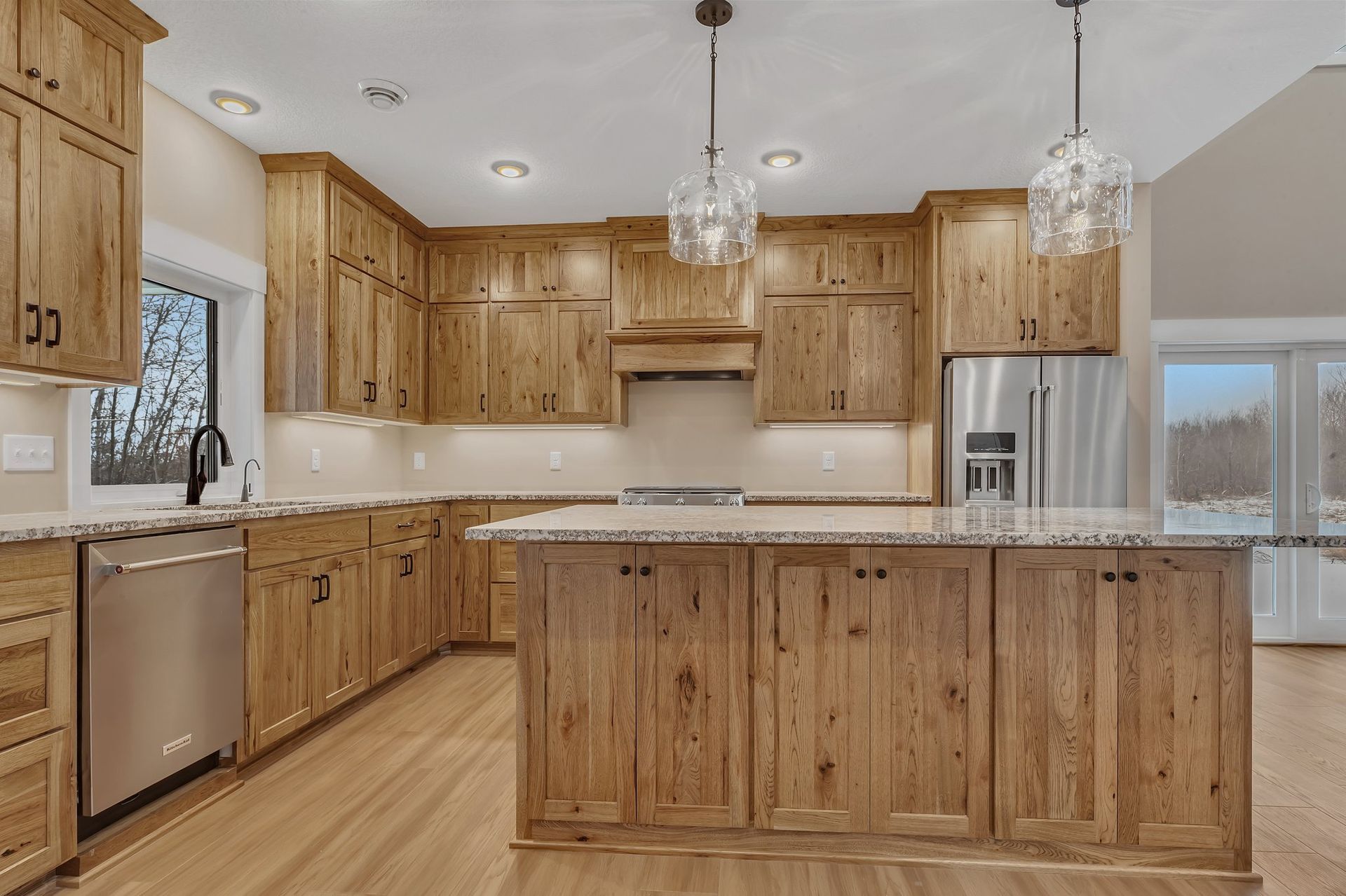 A kitchen with wooden cabinets , granite counter tops , stainless steel appliances and a large island.