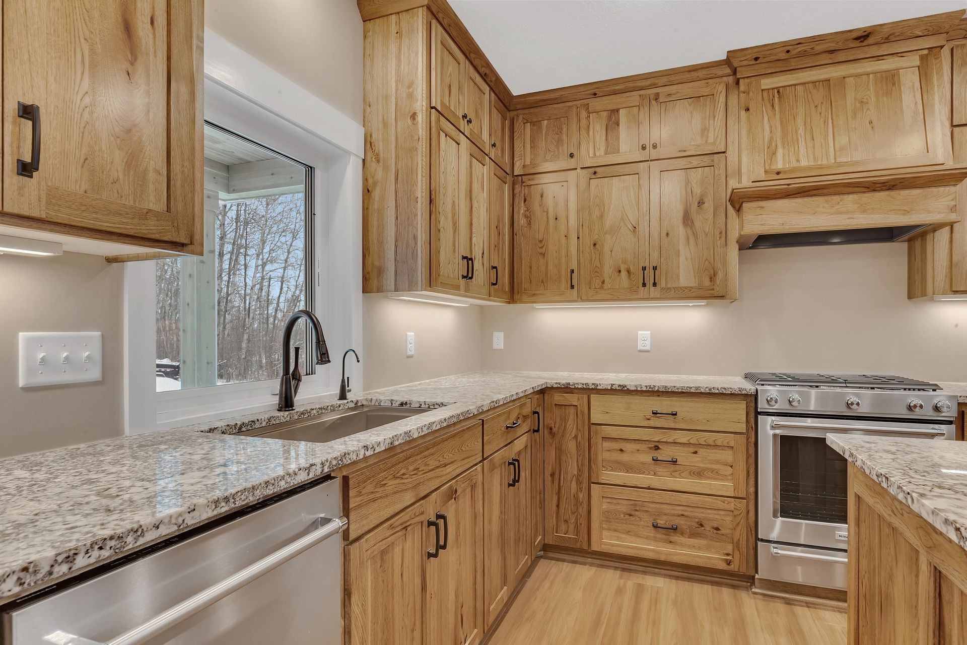 A kitchen with wooden cabinets , granite counter tops , stainless steel appliances and a sink.