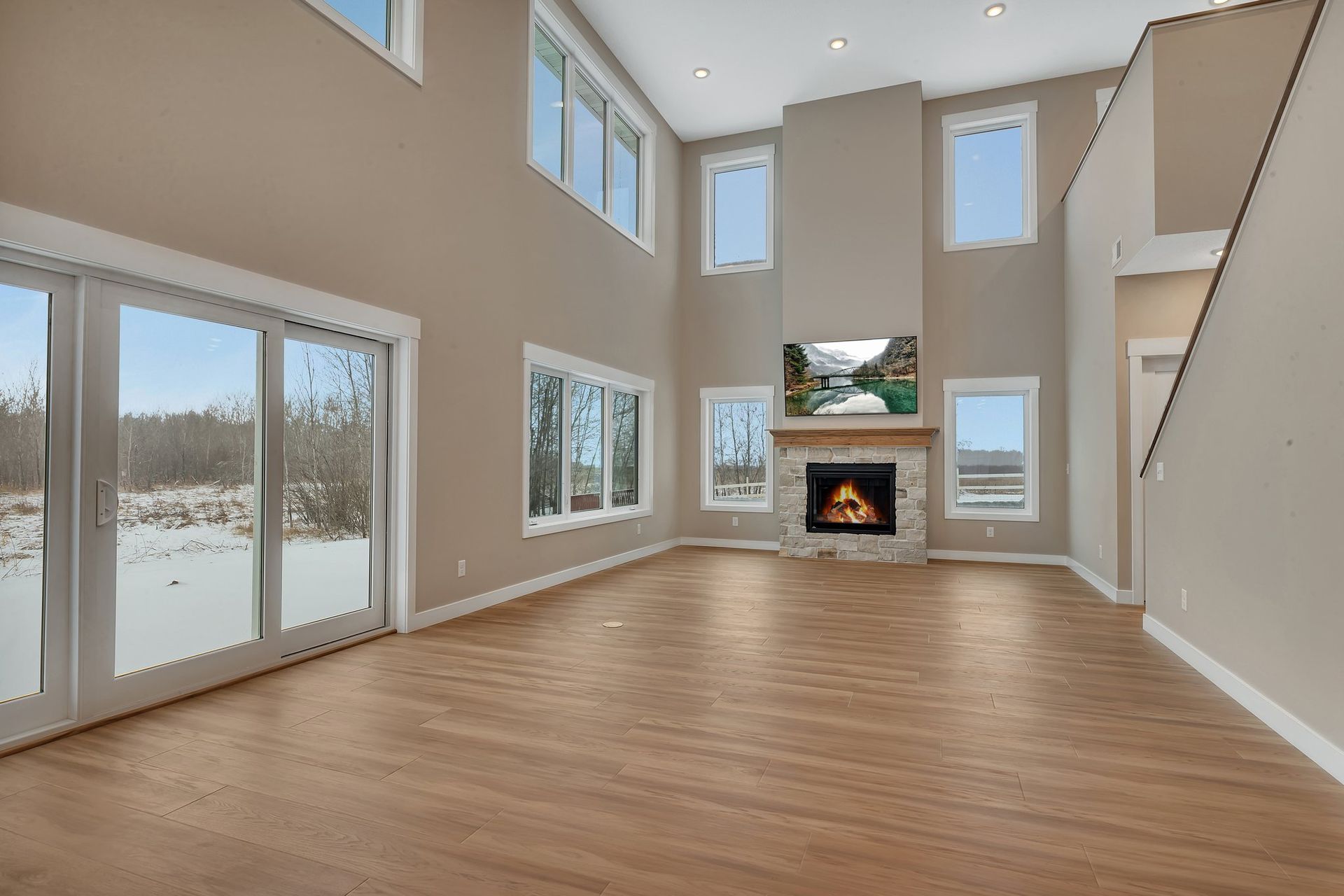 An empty living room with a fireplace and lots of windows.
