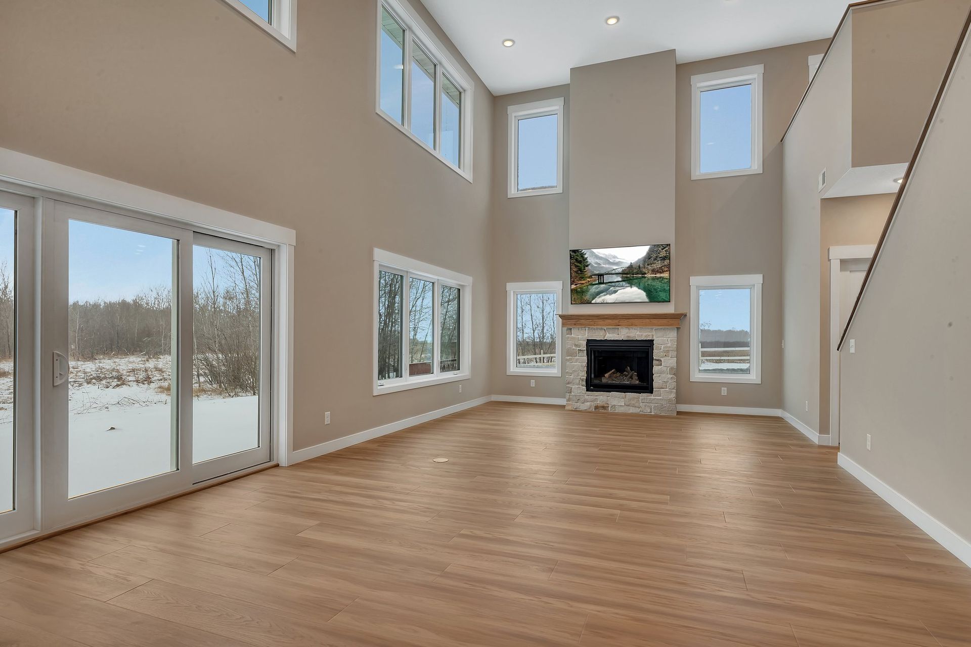 An empty living room with a fireplace and lots of windows.