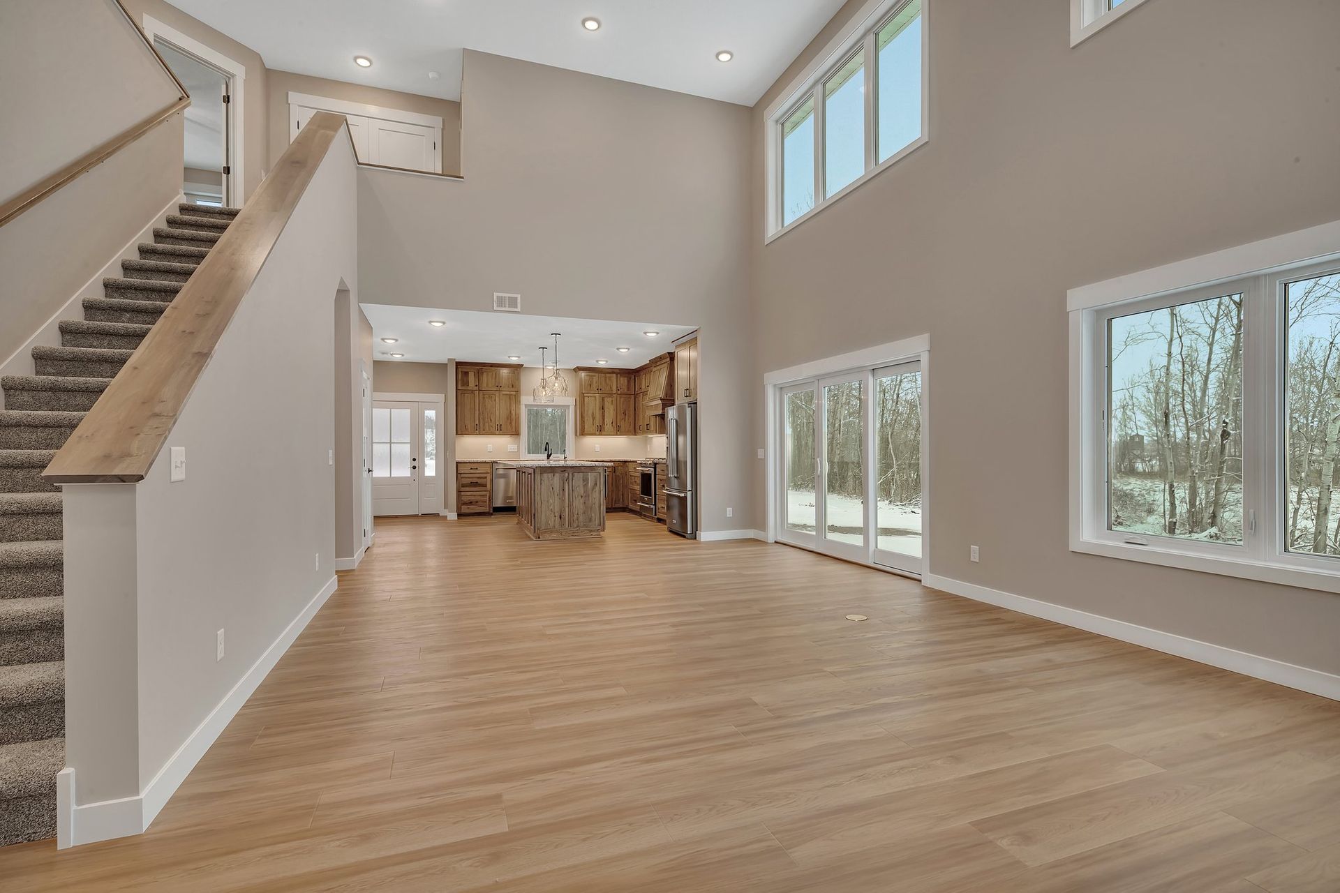 A large empty room with hardwood floors and stairs in a house.