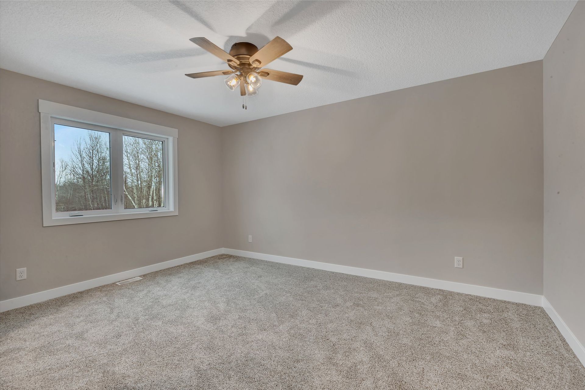 An empty bedroom with a ceiling fan and a window.