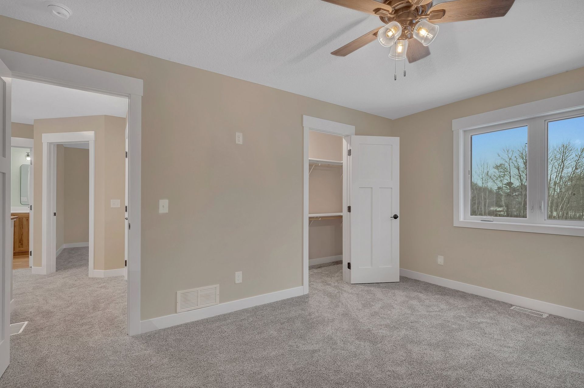 An empty bedroom with a ceiling fan and a window.
