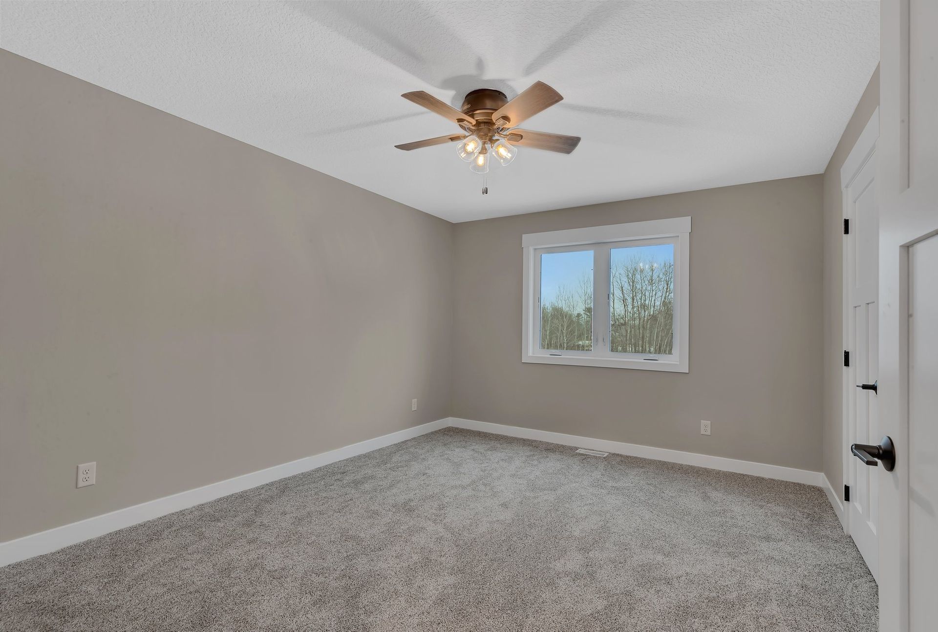 An empty bedroom with a ceiling fan and a window.