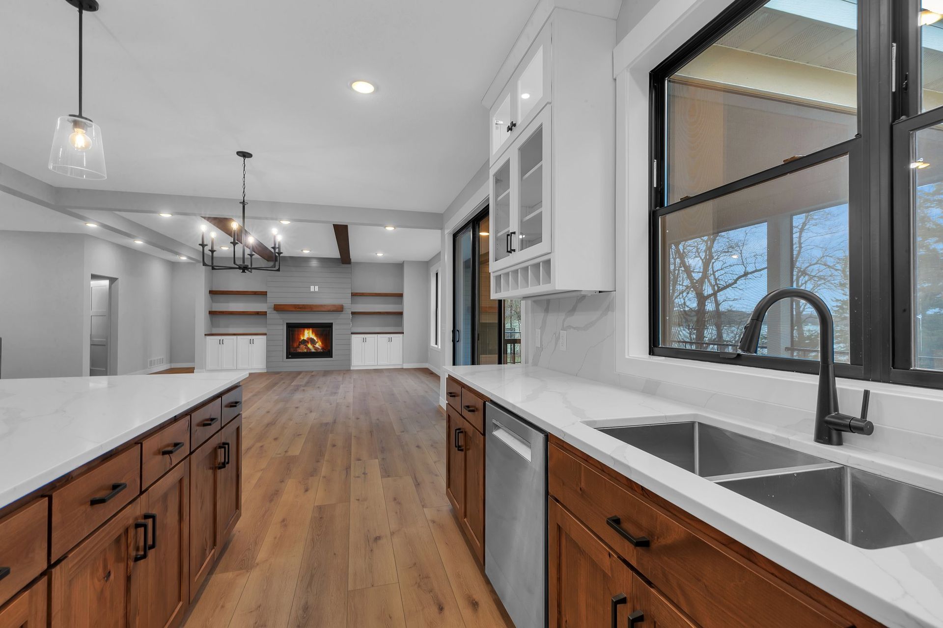 A kitchen with wooden cabinets , stainless steel appliances , a sink and a fireplace.