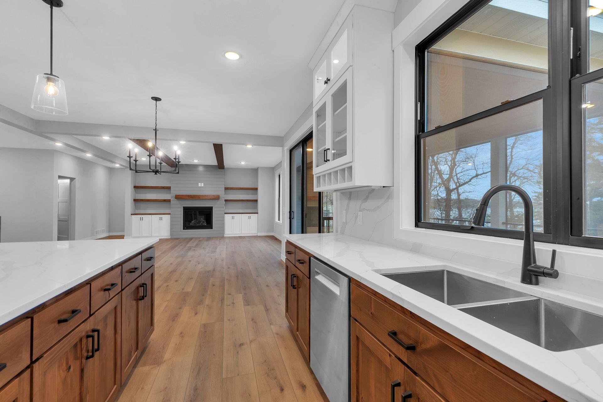 A kitchen with stainless steel appliances , wooden cabinets , white counter tops and a sink.