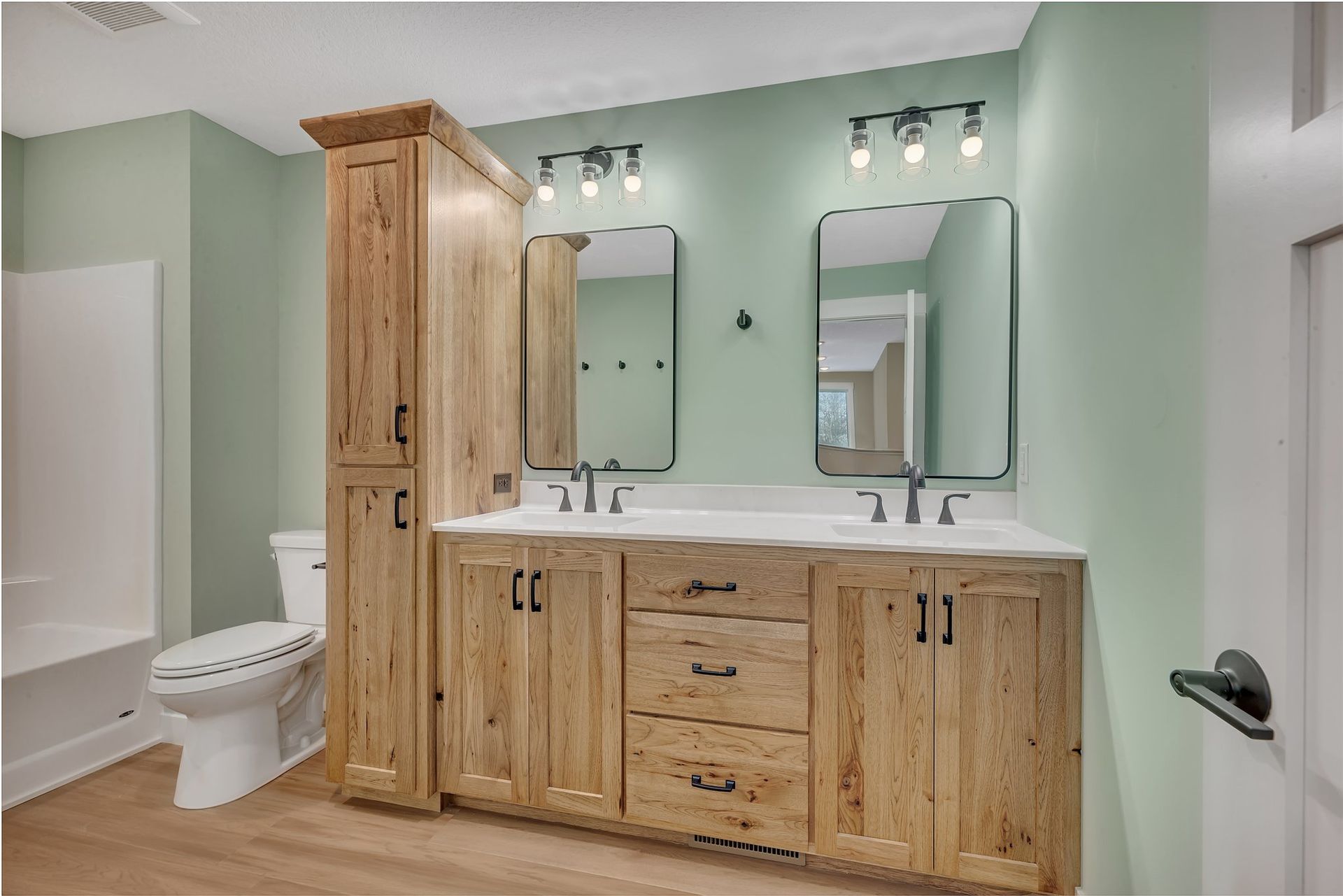 A bathroom with two sinks , a toilet , and two mirrors.