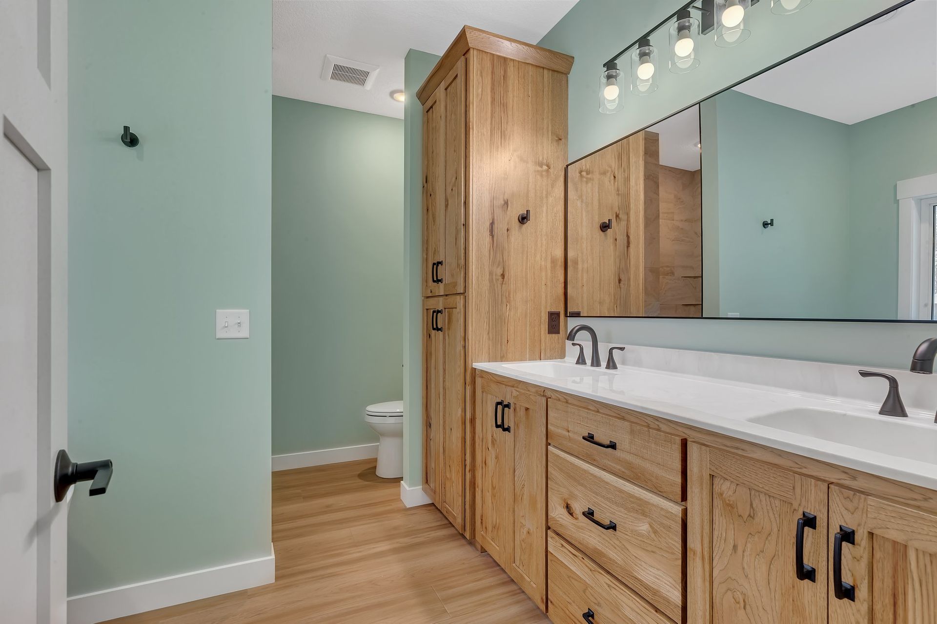 A bathroom with two sinks , a toilet , and a large mirror.