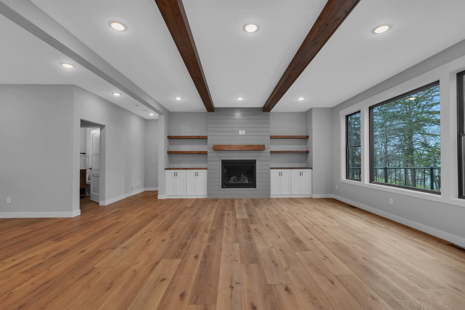 An empty living room with hardwood floors and a fireplace.