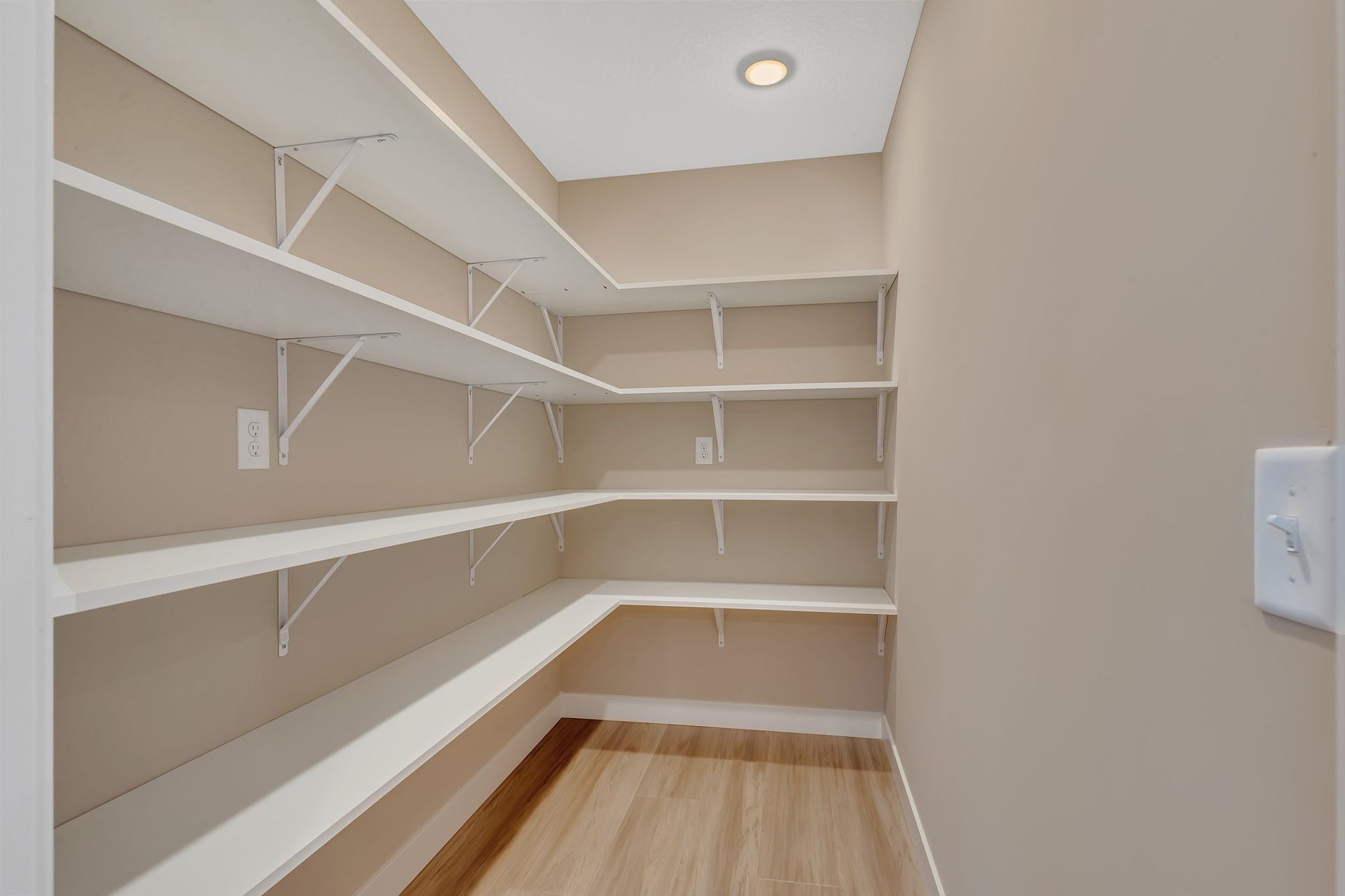 An empty pantry with shelves and a light on the ceiling.