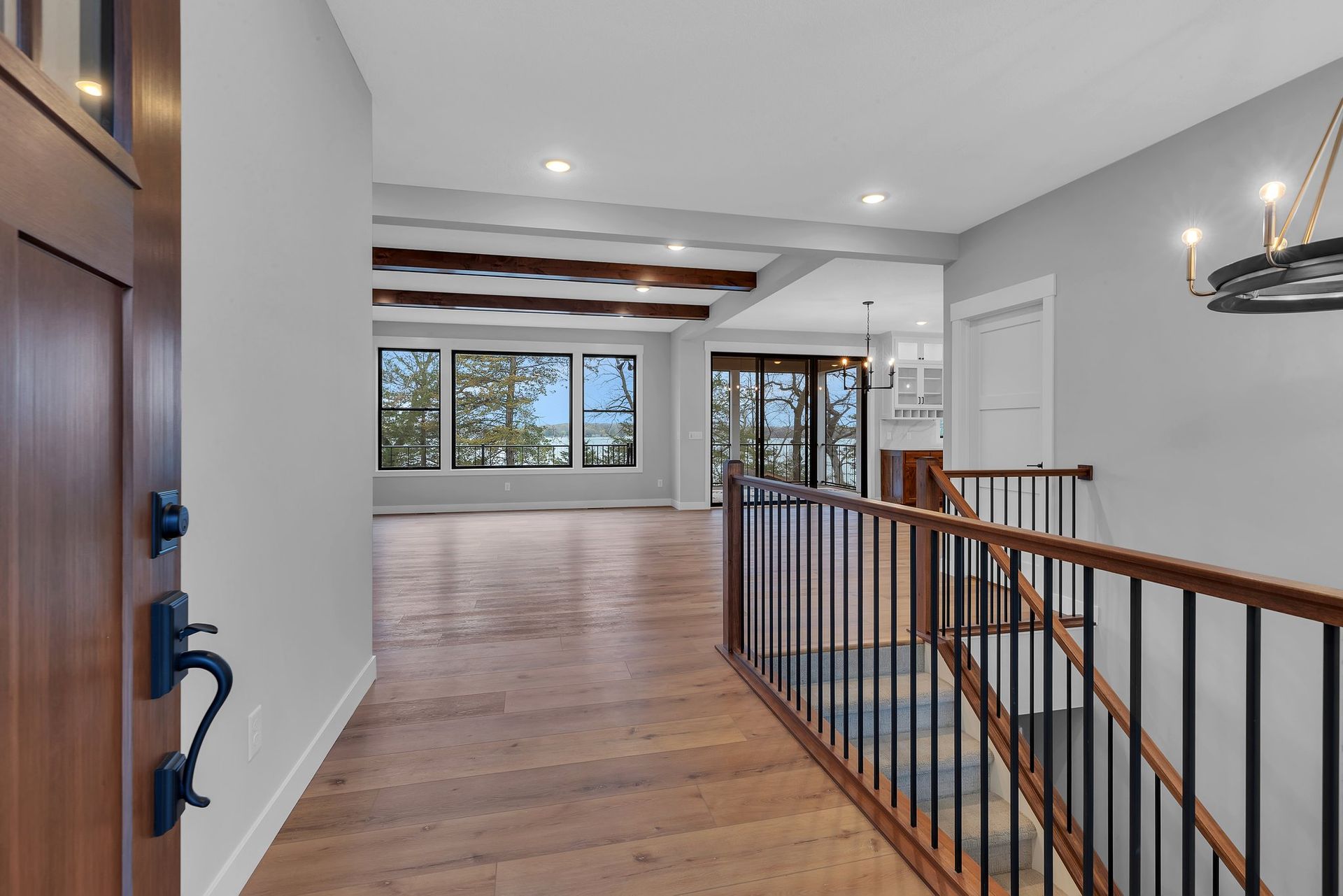 A hallway with wooden floors and stairs in a house.