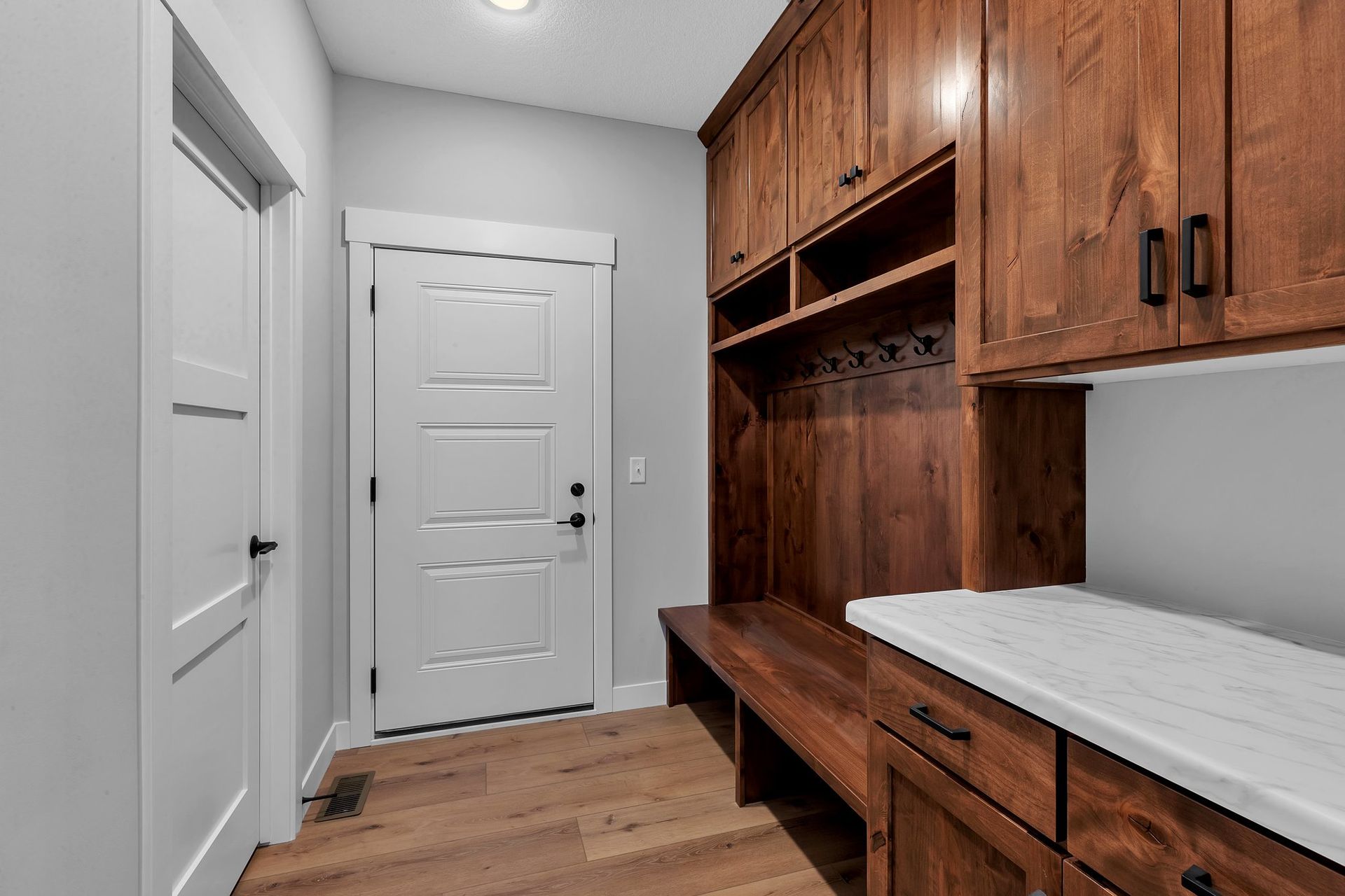 A hallway with wooden cabinets and a white door.