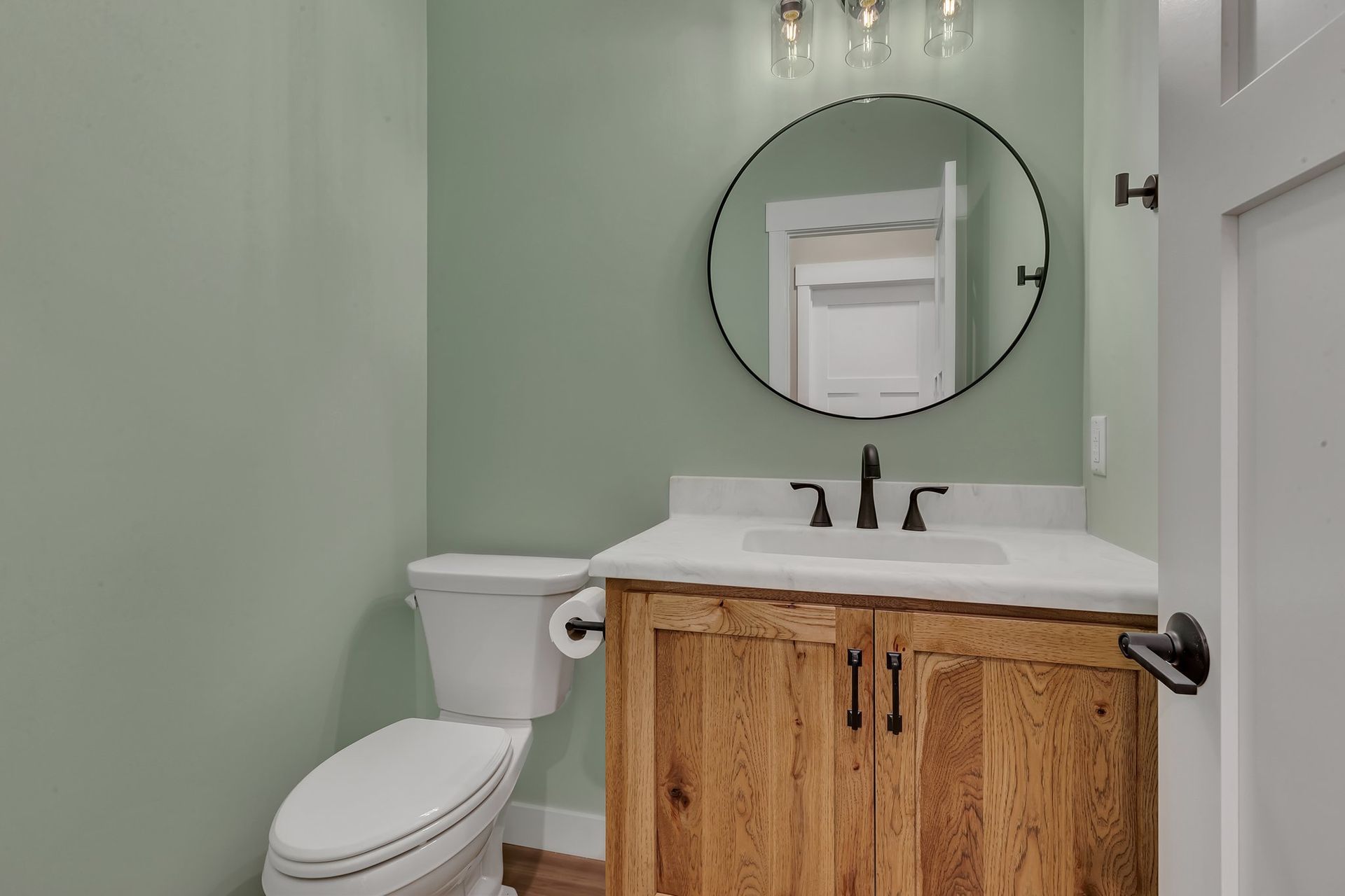 A bathroom with a toilet , sink and mirror.