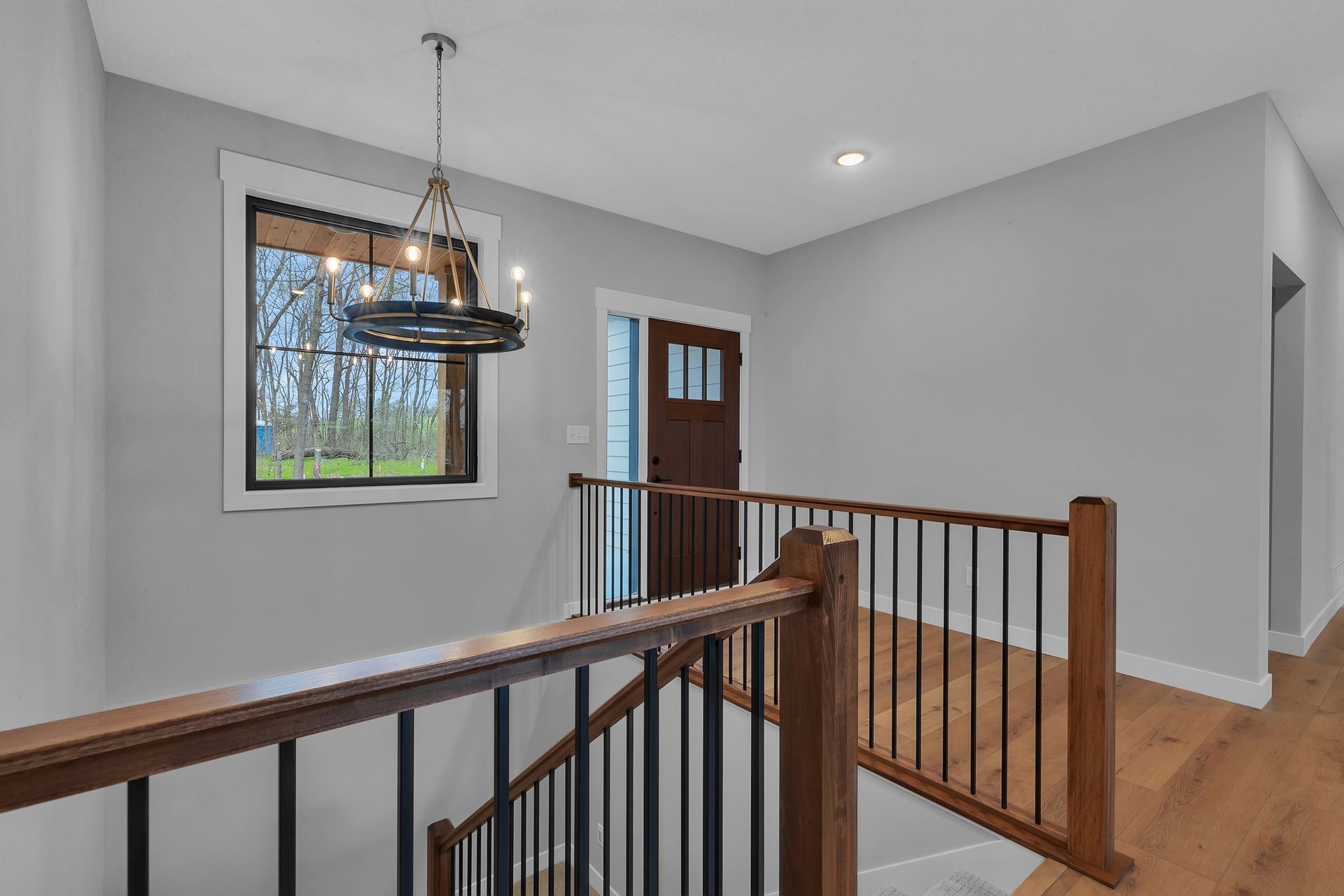 A staircase in a house with a wooden railing and a window.