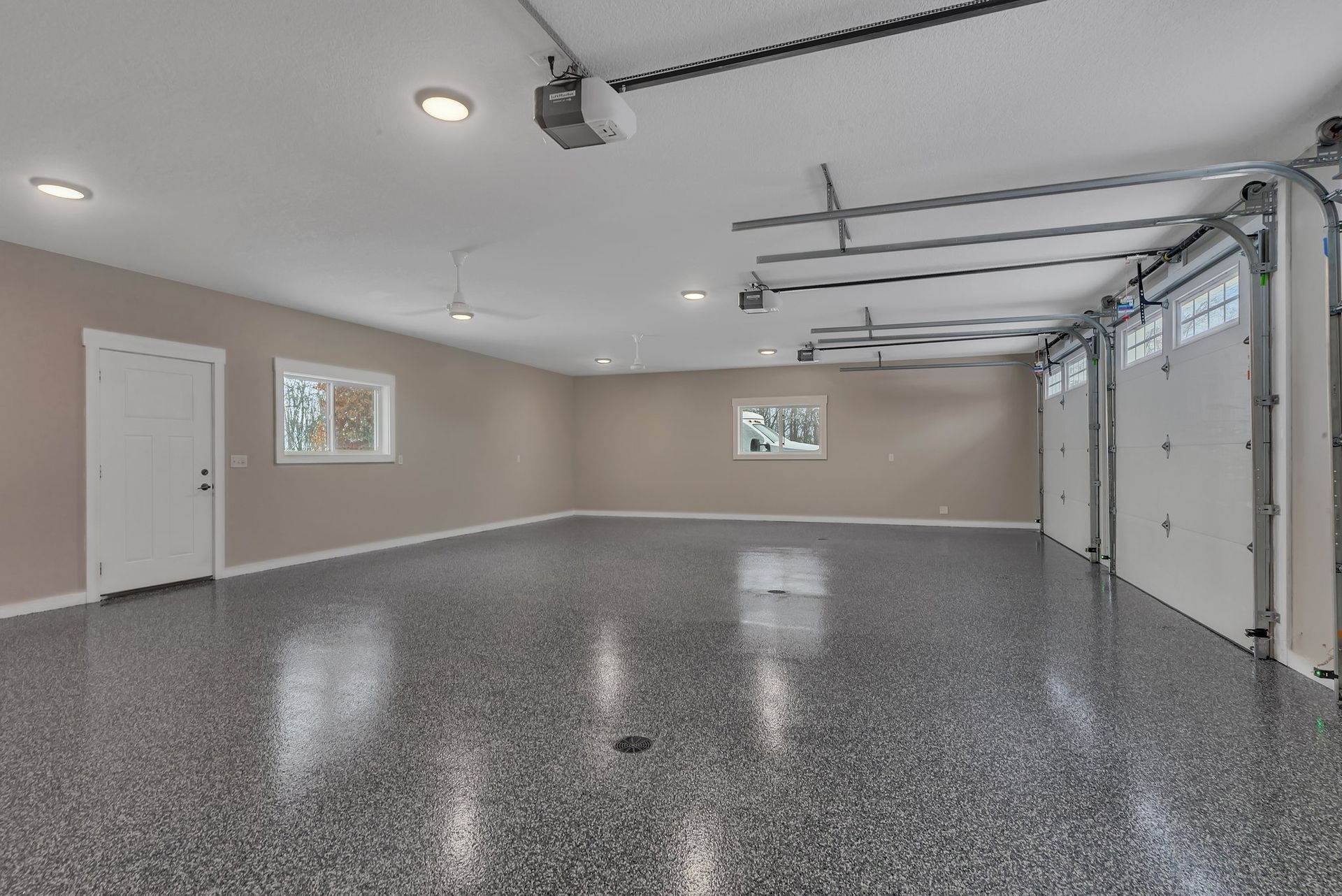 A large empty garage with a garage door open and a ceiling fan.