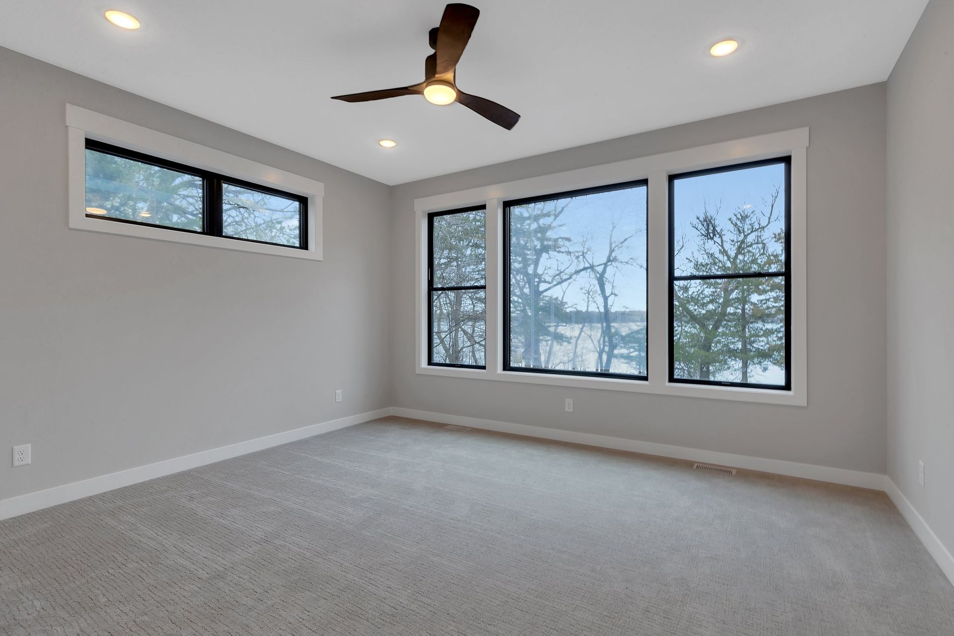 A bedroom with a lot of windows and a ceiling fan.