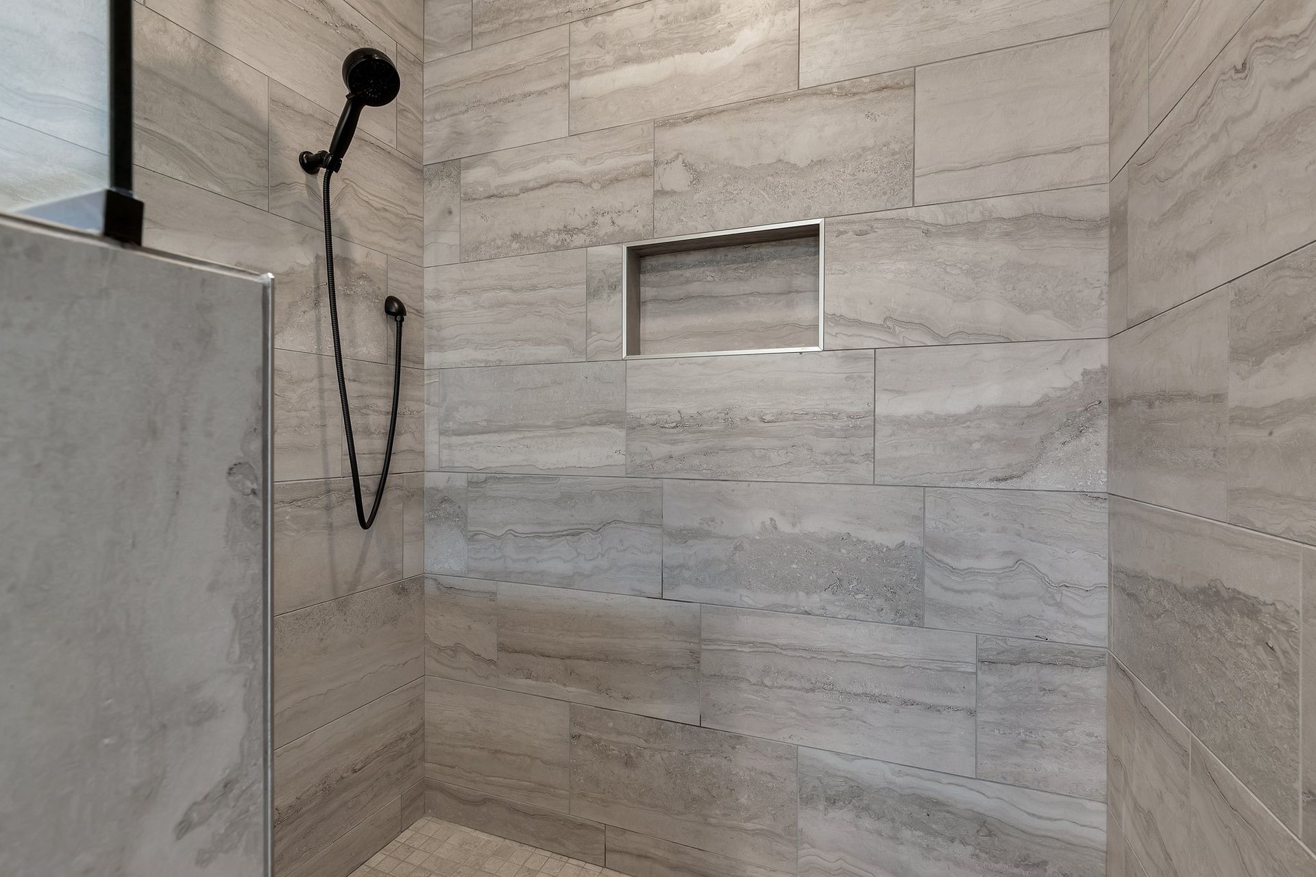 A bathroom with a walk in shower and a shower head.