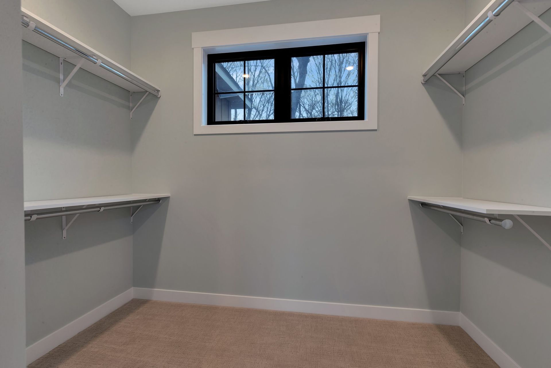 An empty walk in closet with shelves and a window.