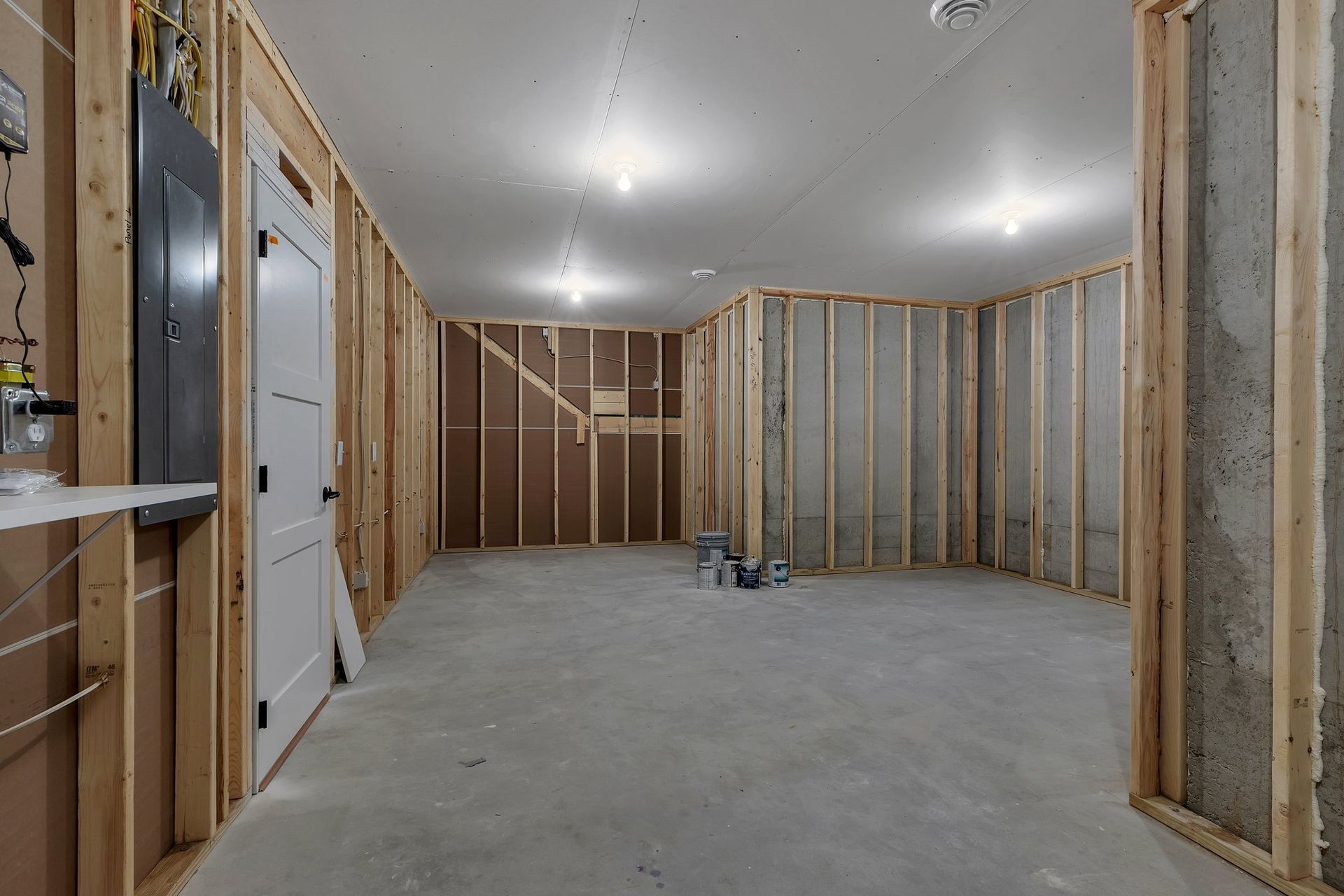 An empty basement with wooden walls and a concrete floor.