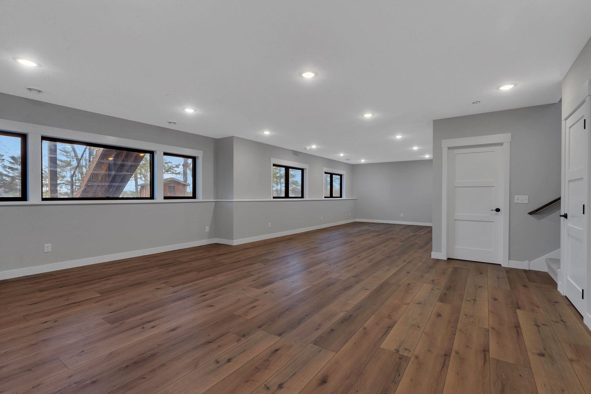 A large empty room with hardwood floors and a staircase.