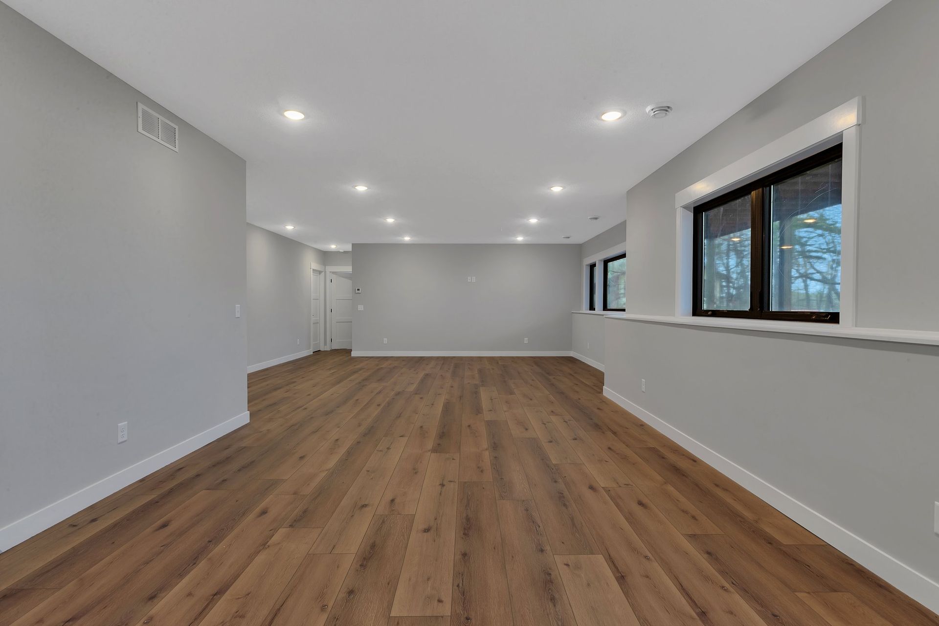 A large empty room with hardwood floors and two windows.