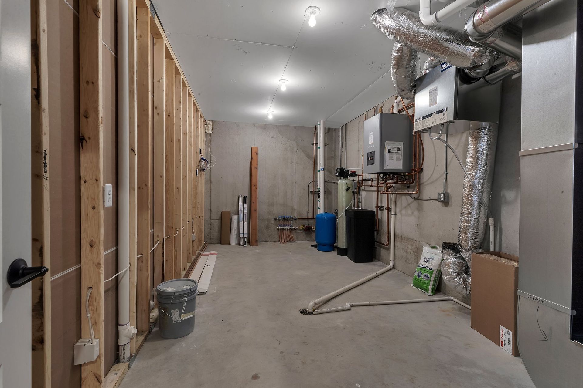 An empty basement with a lot of pipes and a heater.