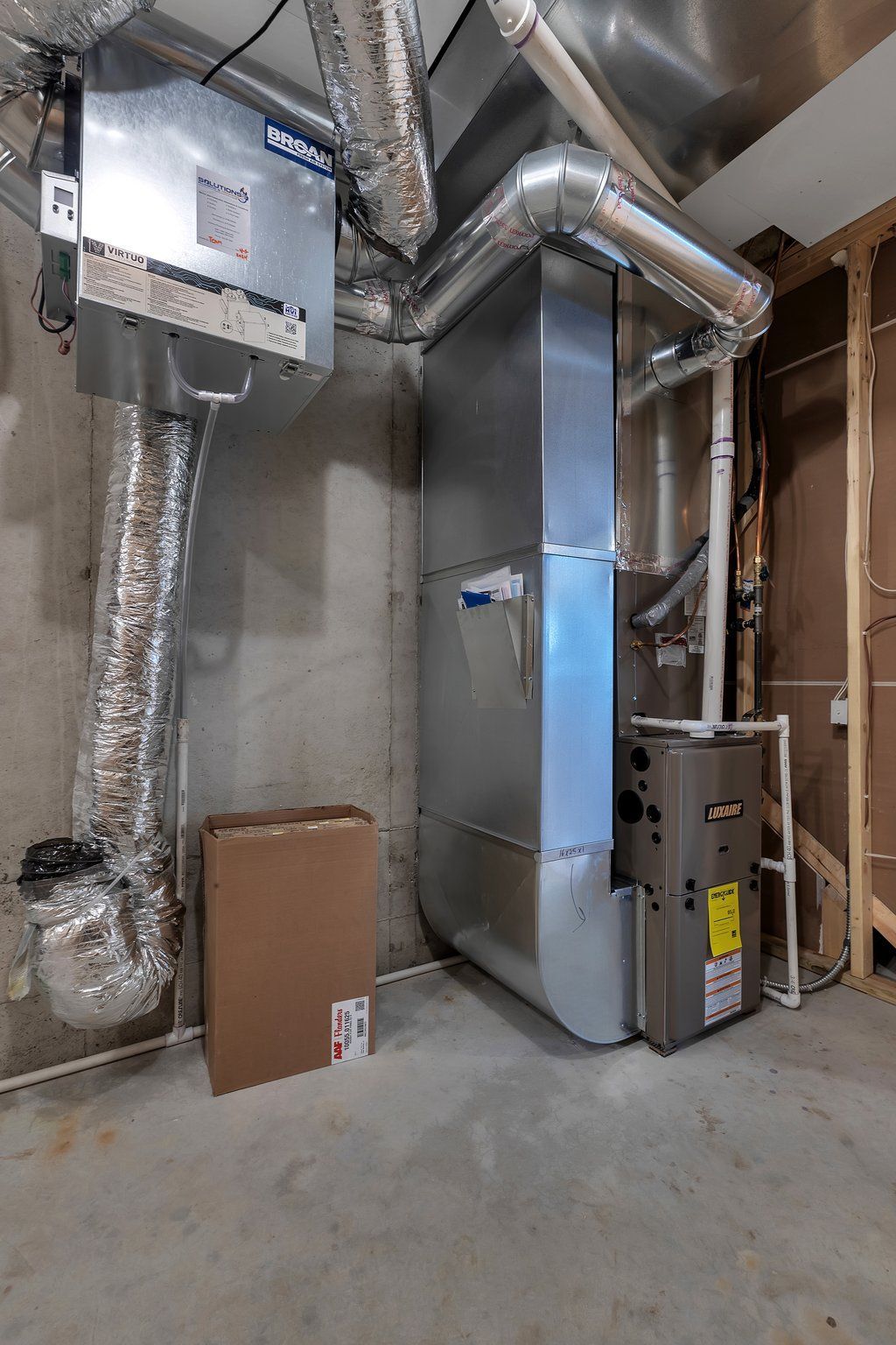 A basement with a furnace and a box on the floor.