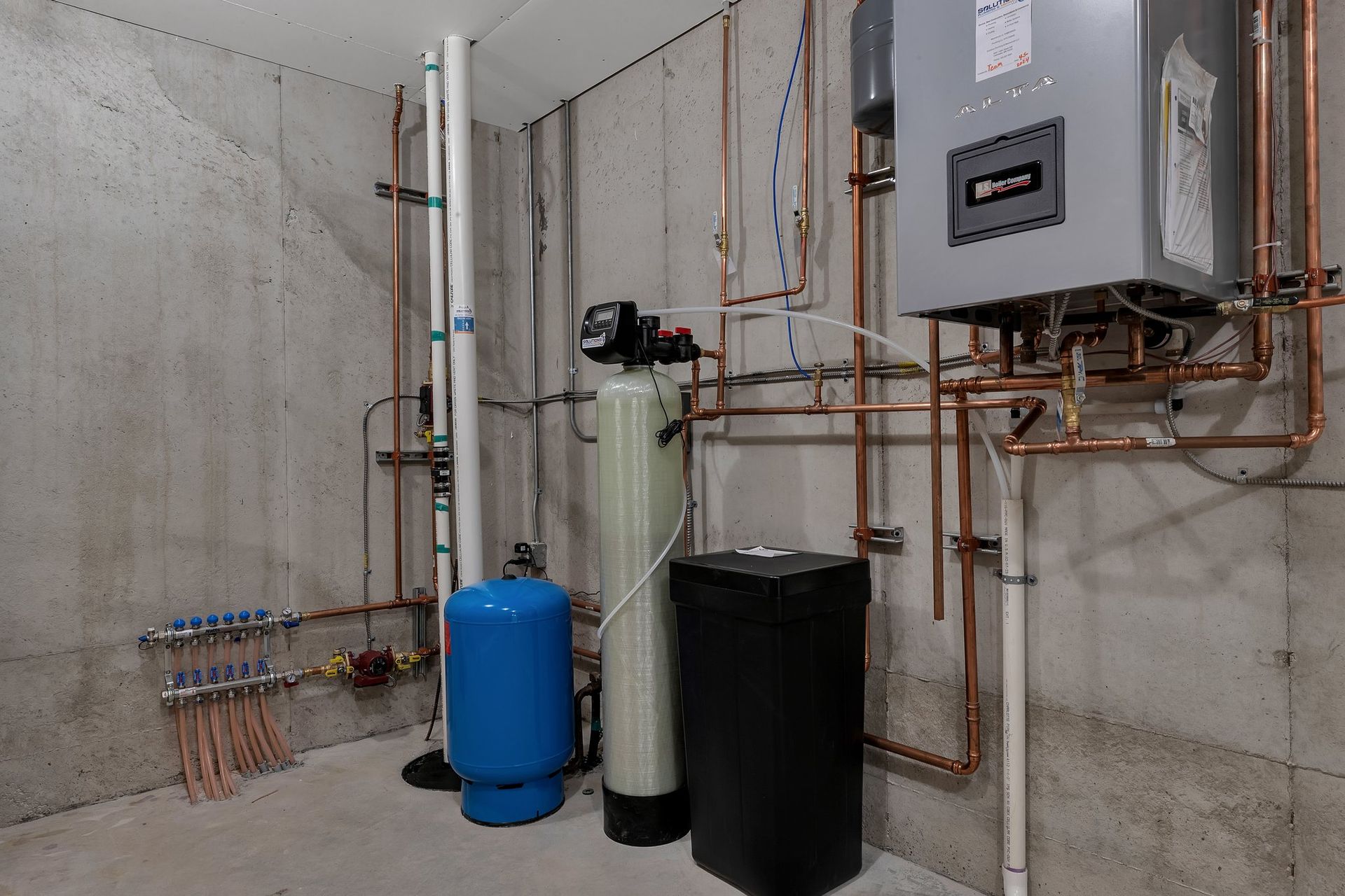 A room with a lot of pipes and a water tank.