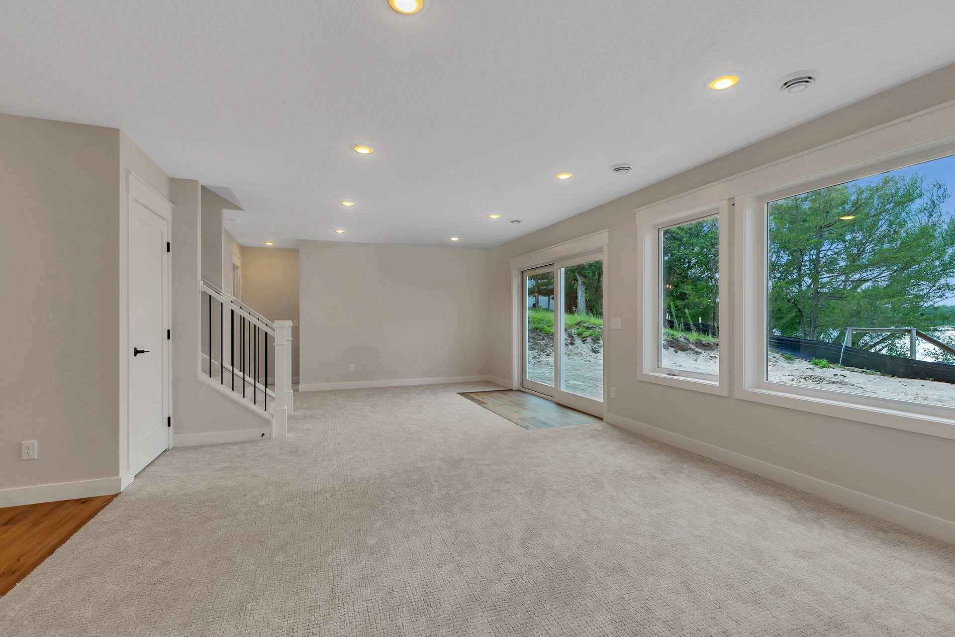 An empty living room with a lot of windows and a staircase.