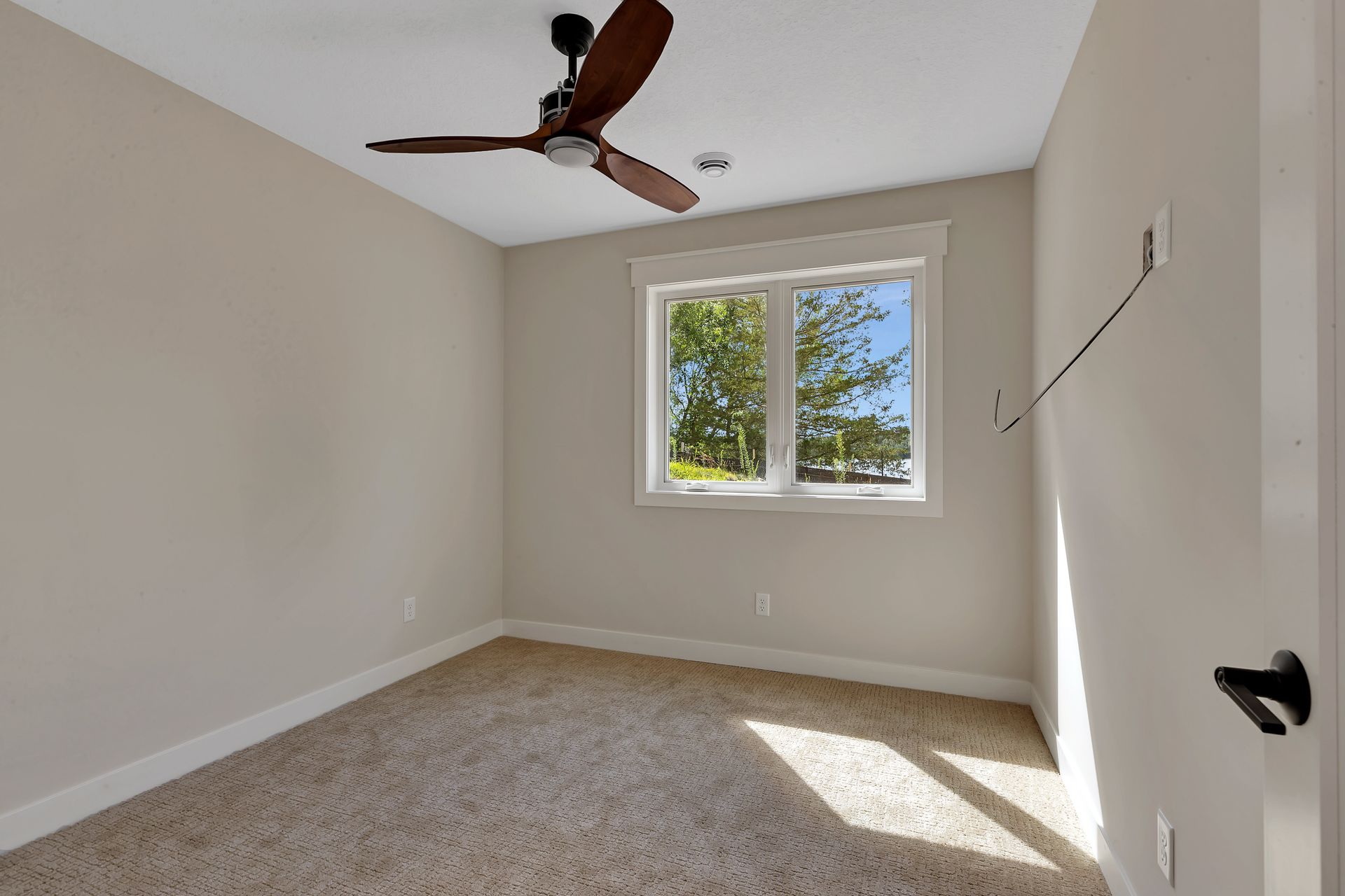 An empty bedroom with a ceiling fan and a window.