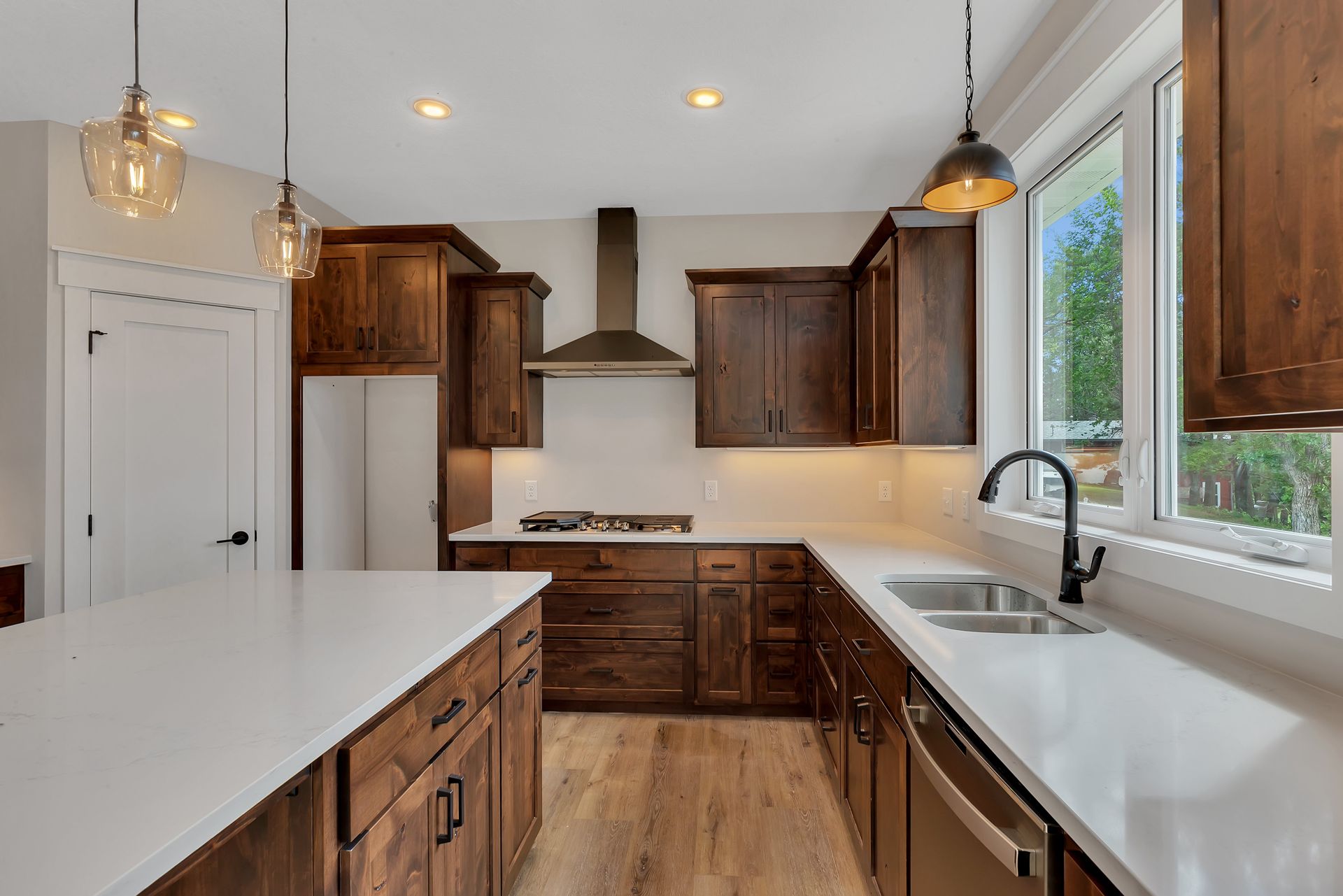A kitchen with wooden cabinets , white counter tops , stainless steel appliances and a large island.