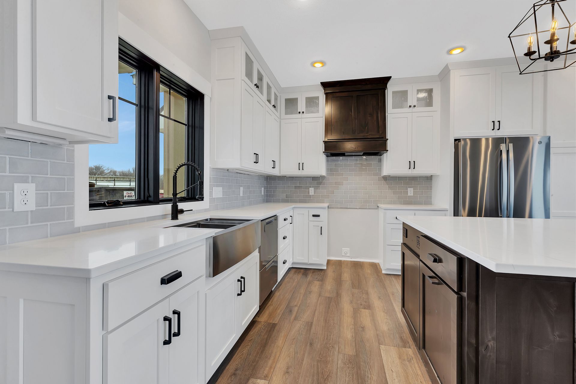 A kitchen with white cabinets , stainless steel appliances , a sink , and a large island.