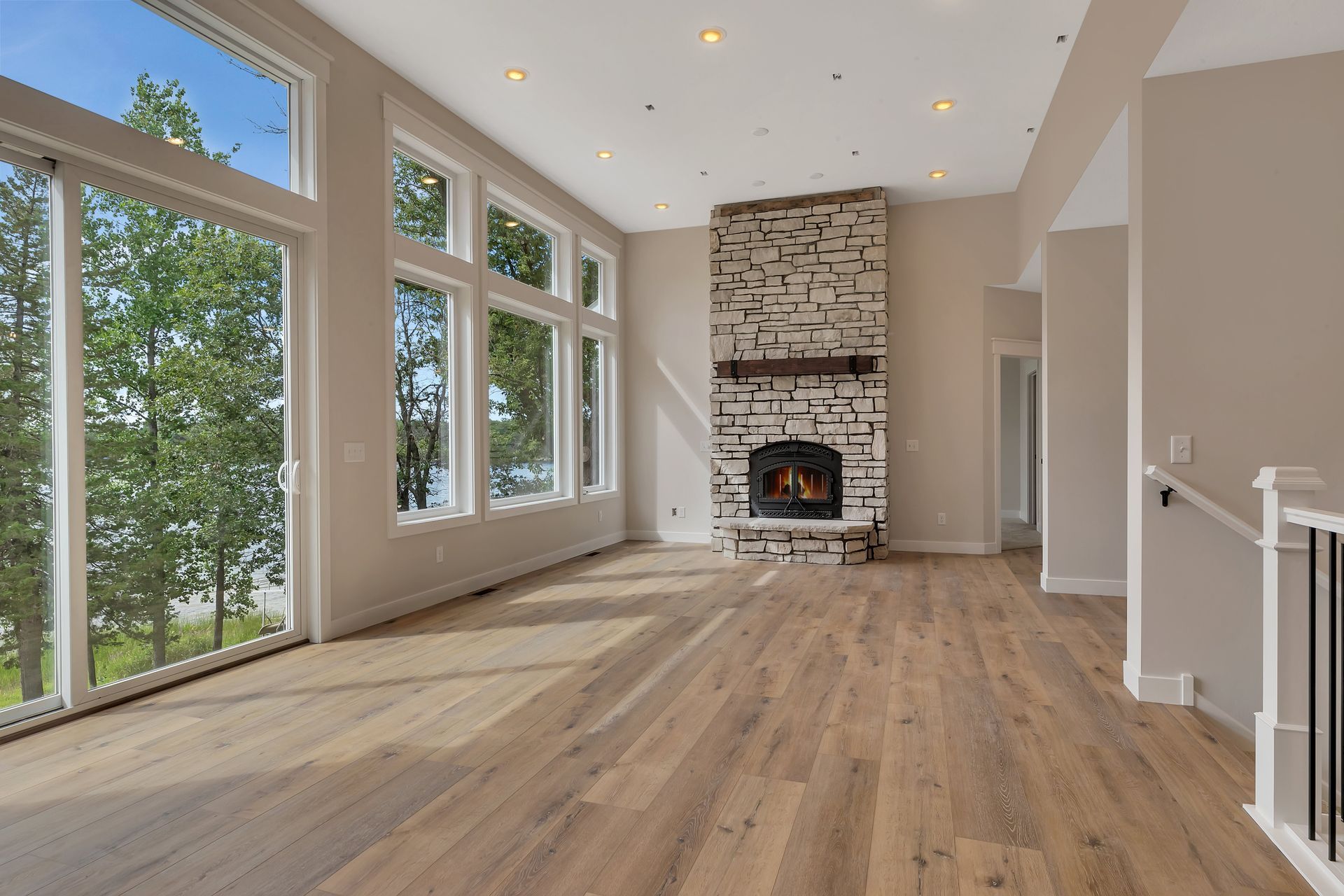 An empty living room with a fireplace and lots of windows.